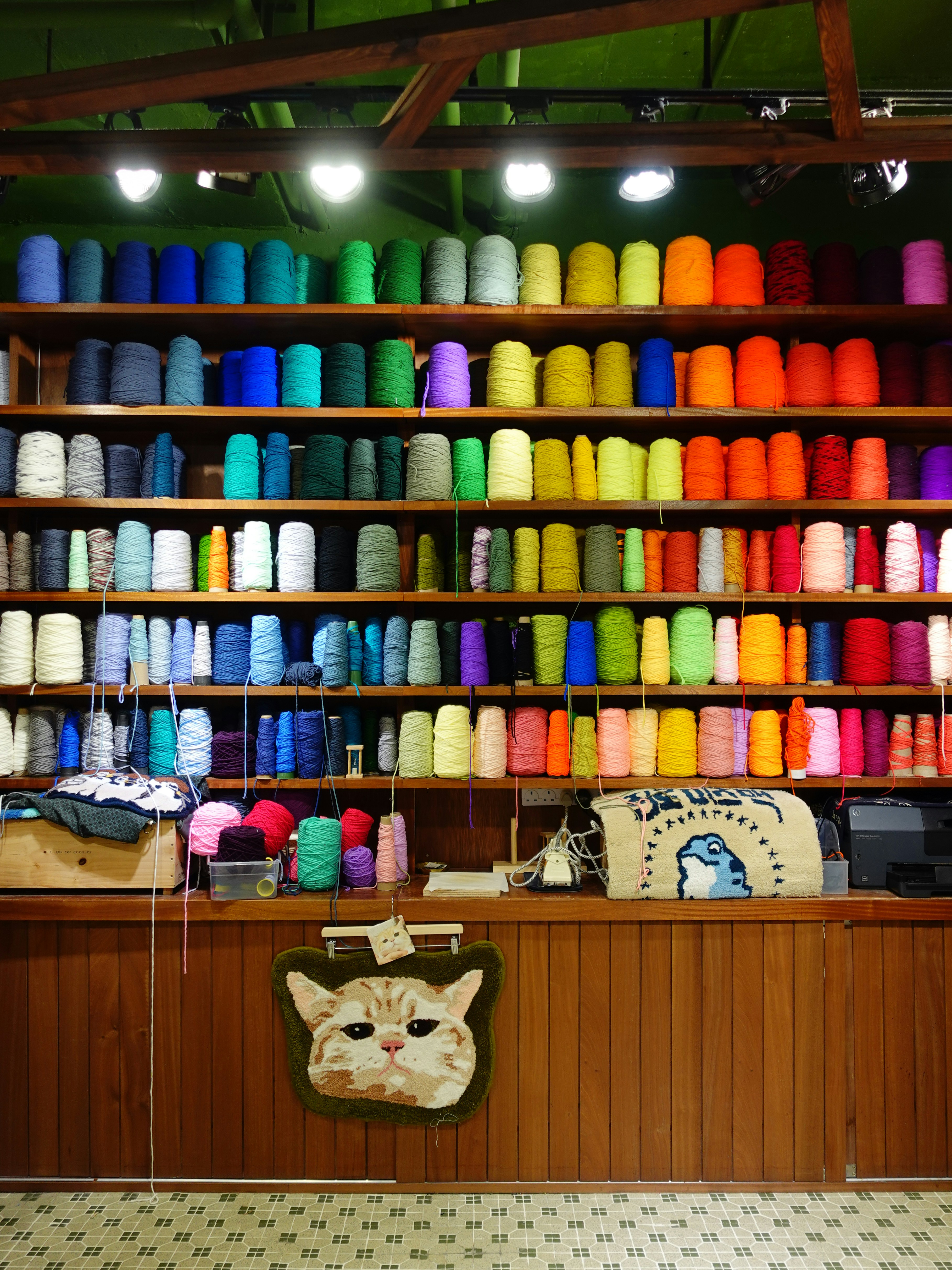 Colorful yarn spools fill shelves in an organized display.
