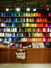 Colorful yarn spools fill shelves in an organized display.