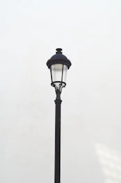A single lamp post against a white wall.