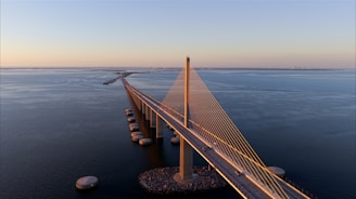 A long bridge spans across the water at sunset.