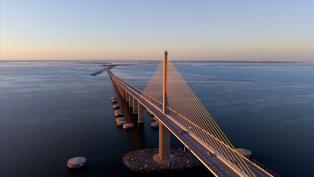 A long bridge spans across the water at sunset.