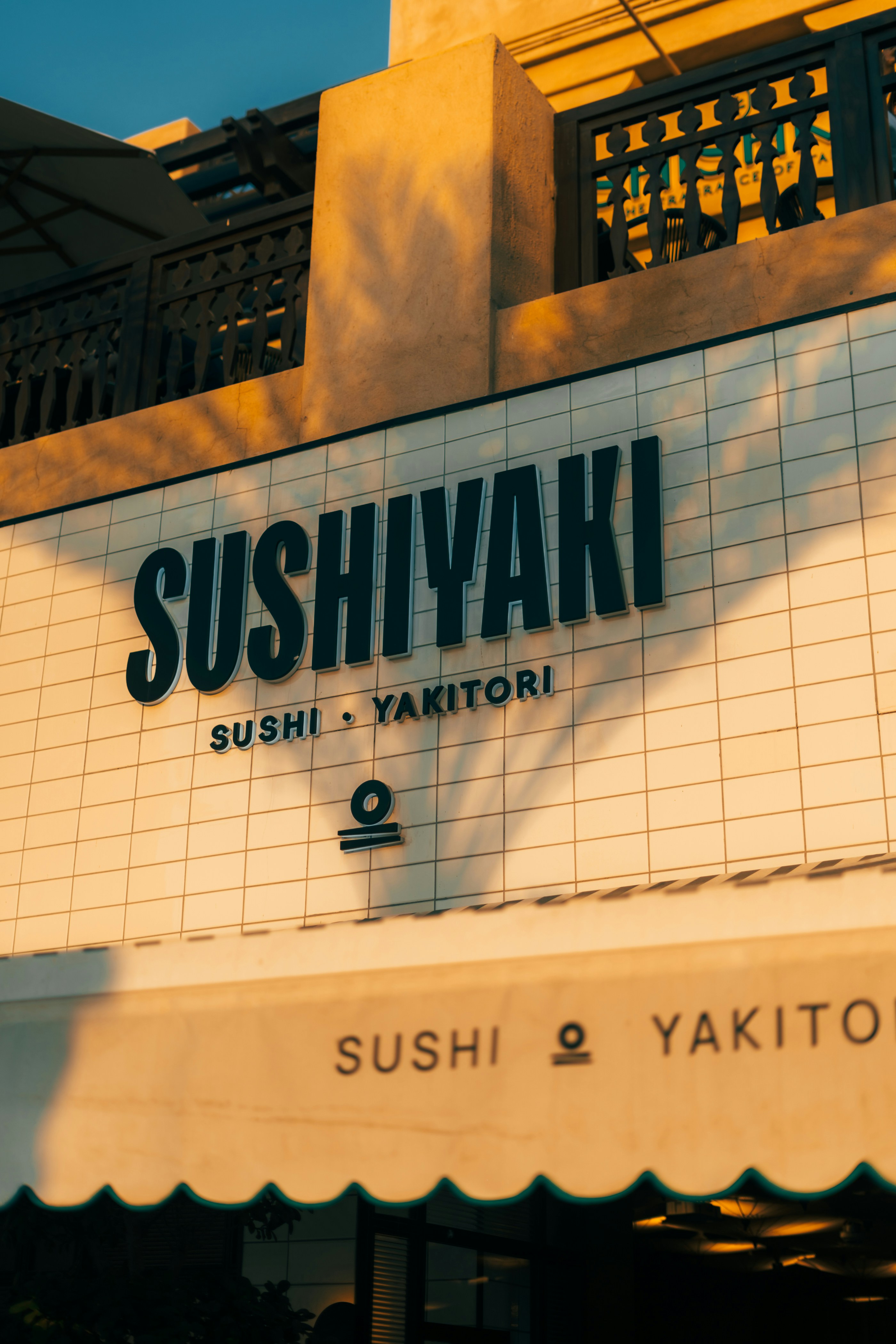 Sushiyaki restaurant's exterior sign in golden sunlight.
