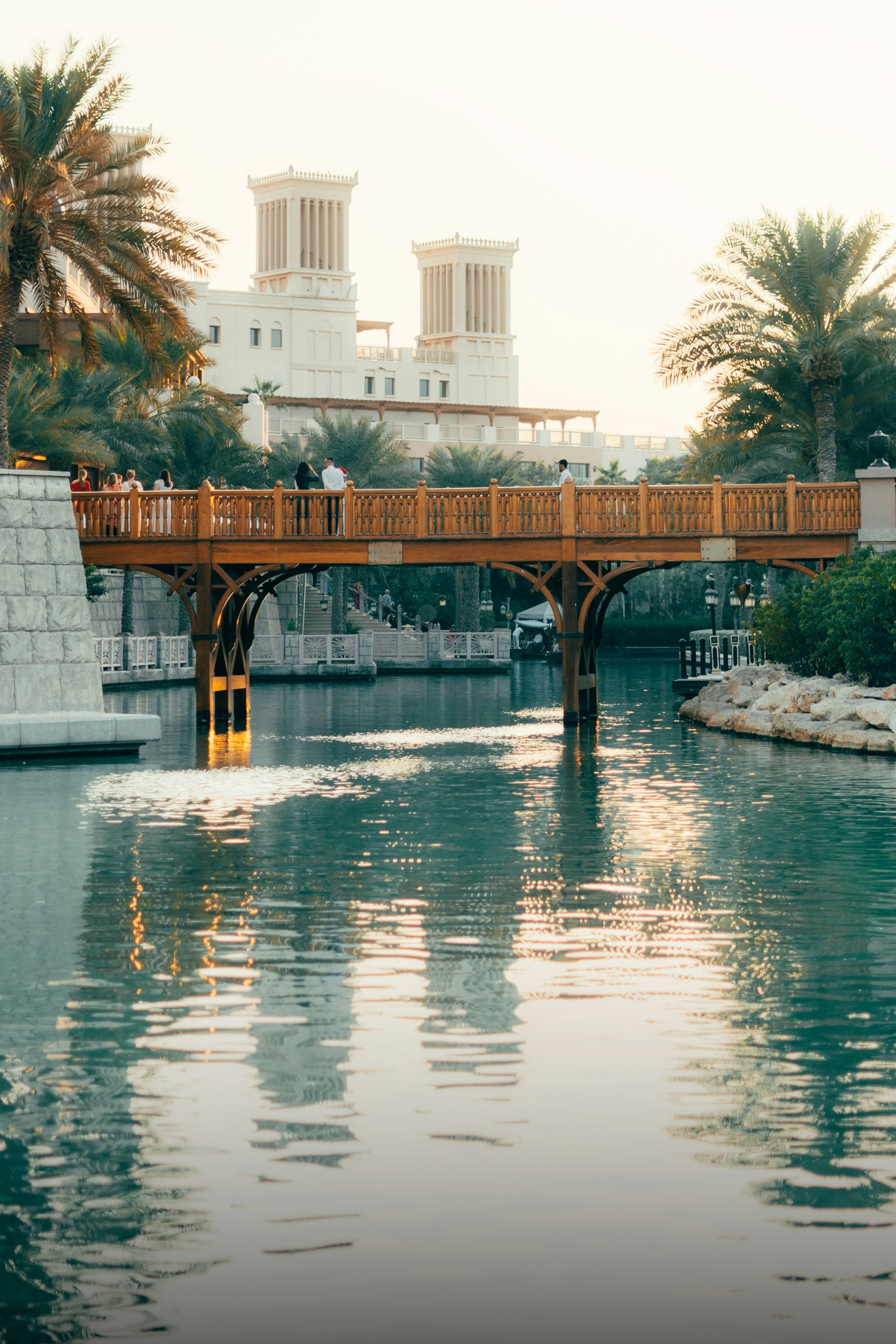 Wooden bridge spans a waterway in a serene setting.