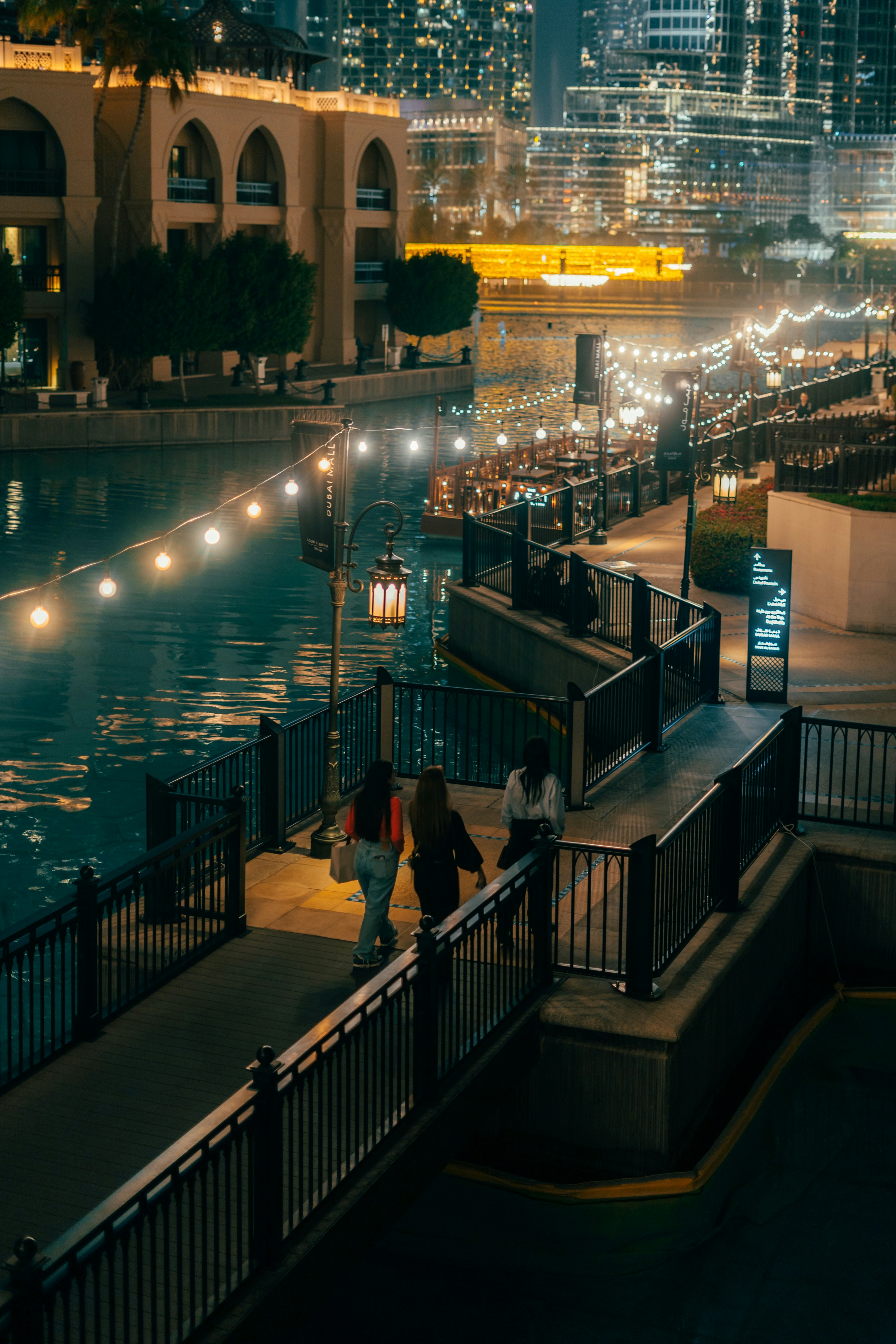 People enjoy a nighttime stroll by the illuminated canal.