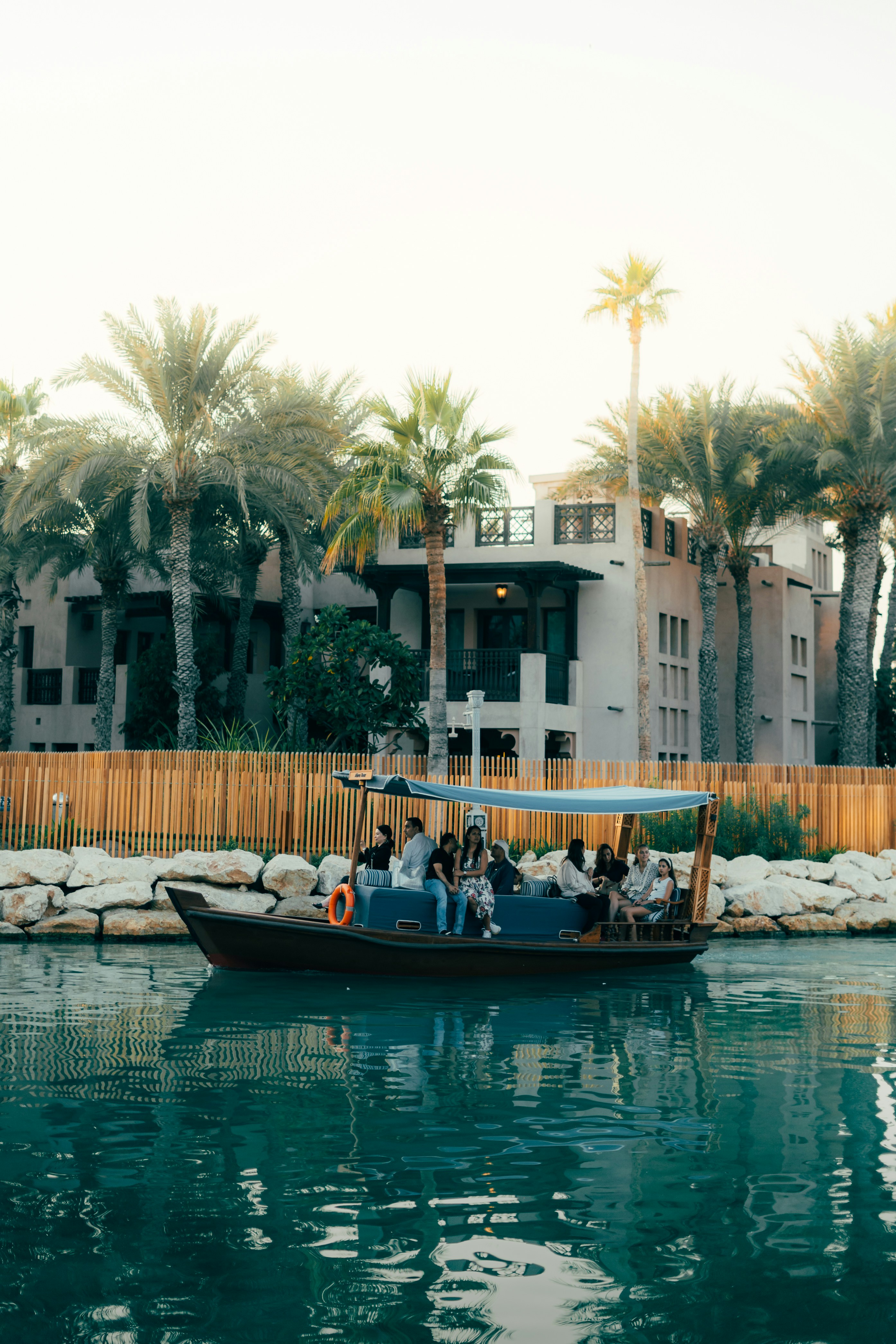 A boat carries people on the water near buildings.