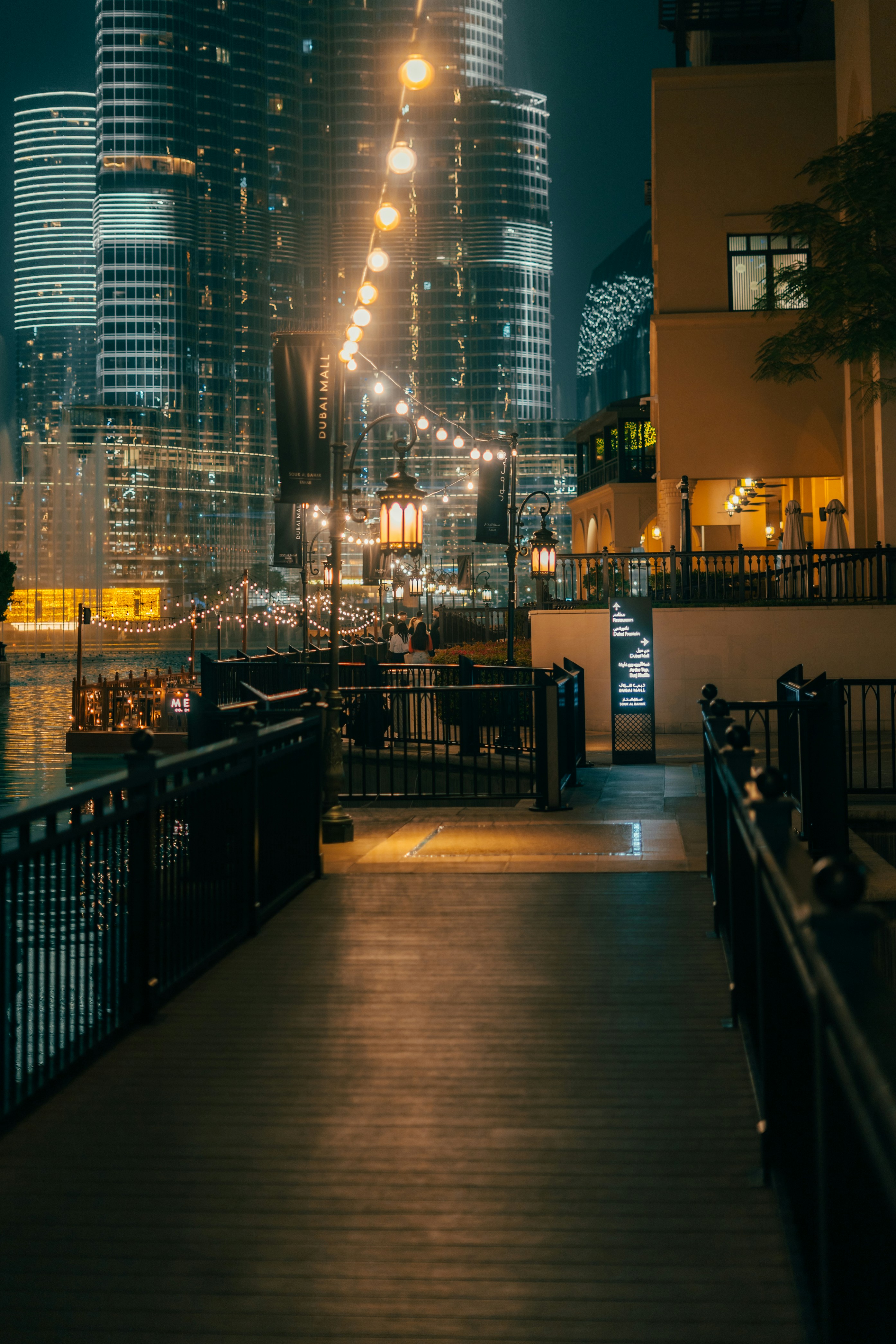 Nighttime view of city buildings and a walkway.