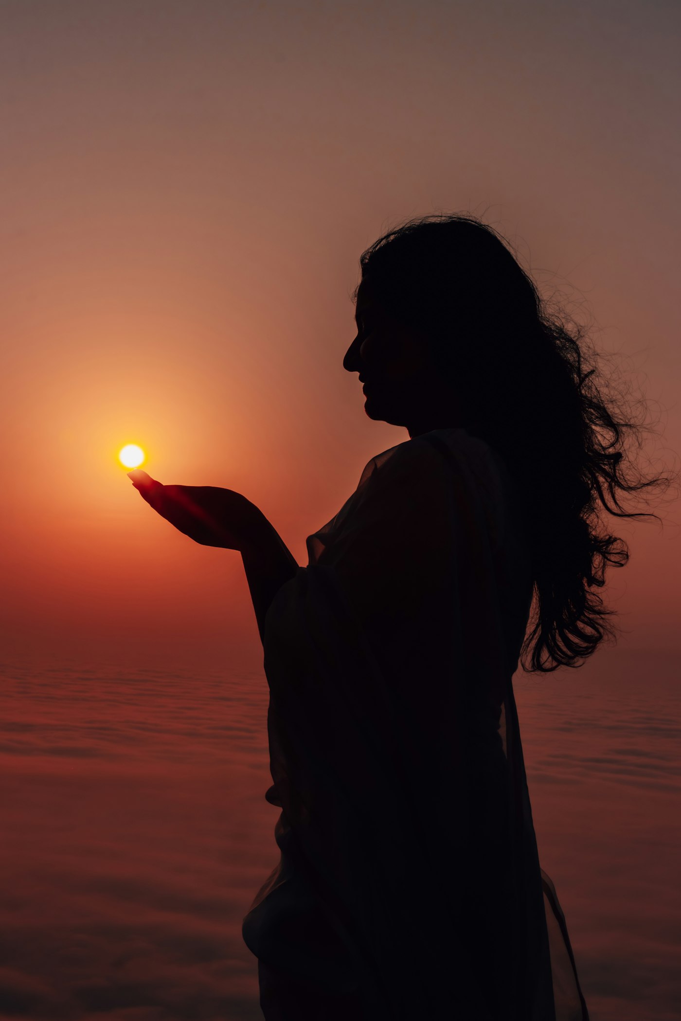 Woman holding her hands up to the setting sun
