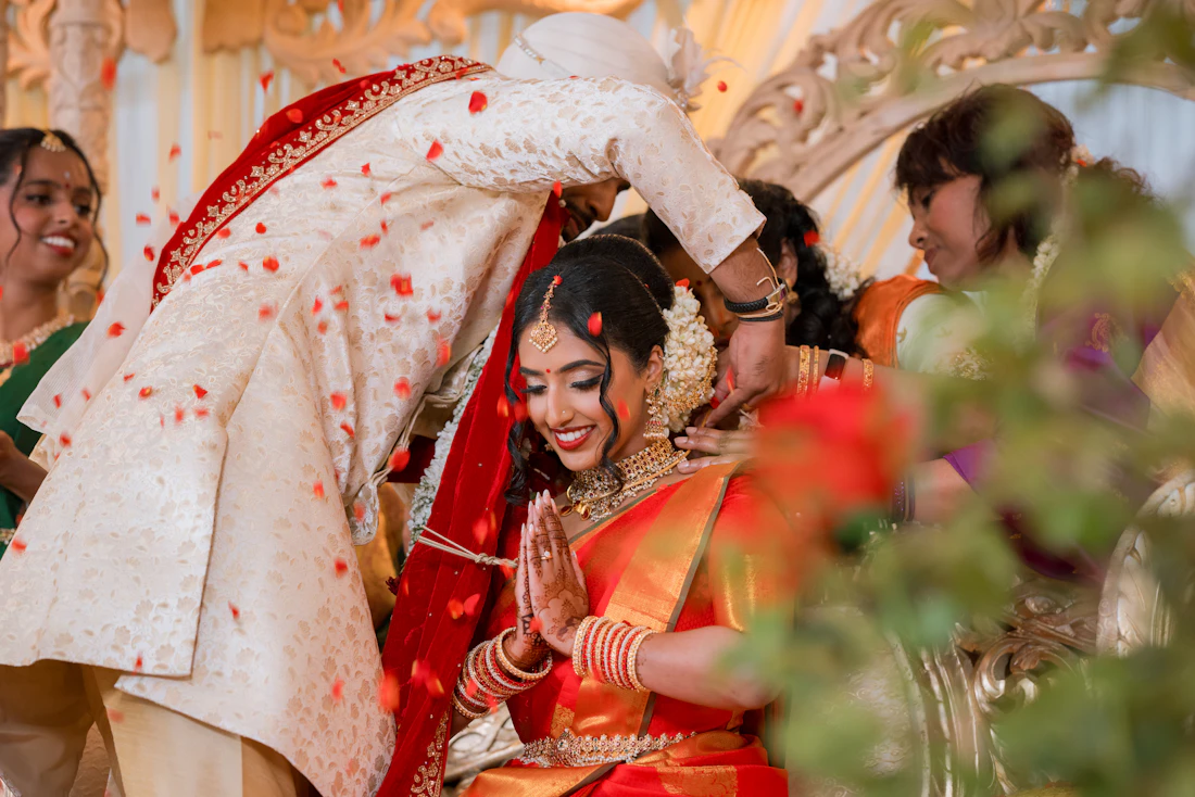 Bride and groom during a South Indian wedding ceremony as rose petals fall around them