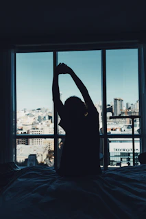 Person stretches near a city view window.