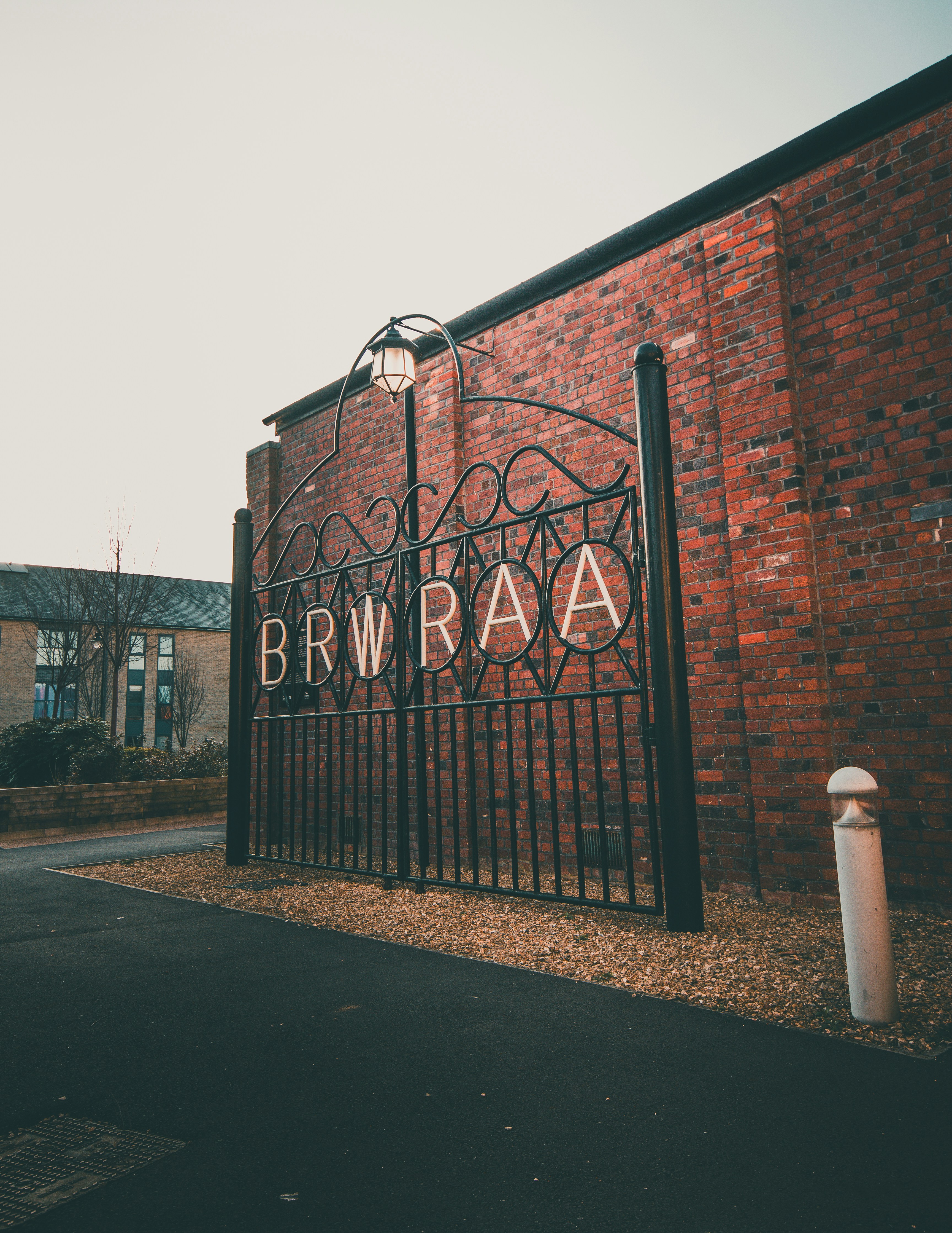 Metal gate reading brwraa stands before a red brick building.