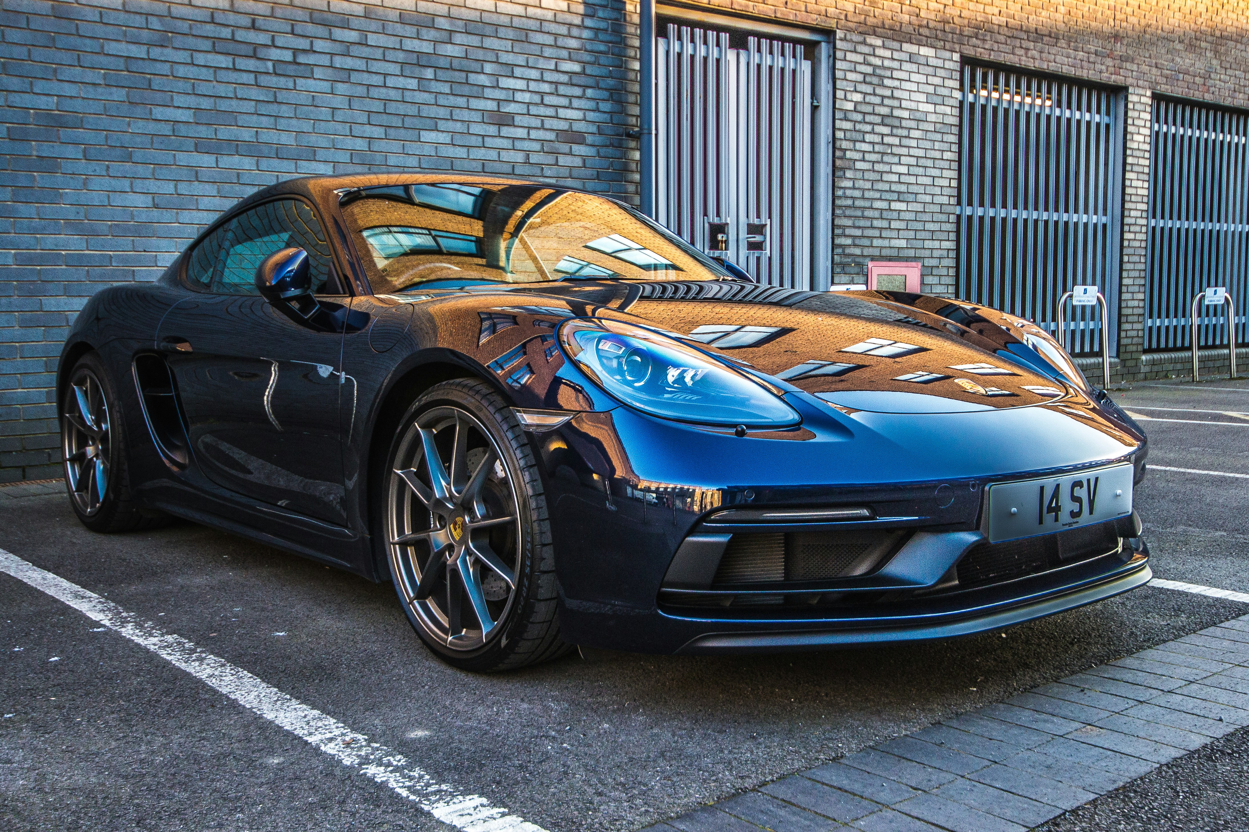 A sleek, blue porsche is parked outside.
