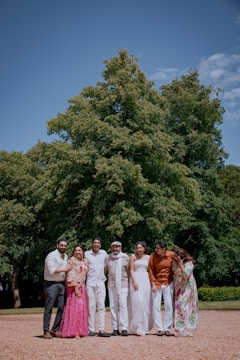A family poses together under a big tree.