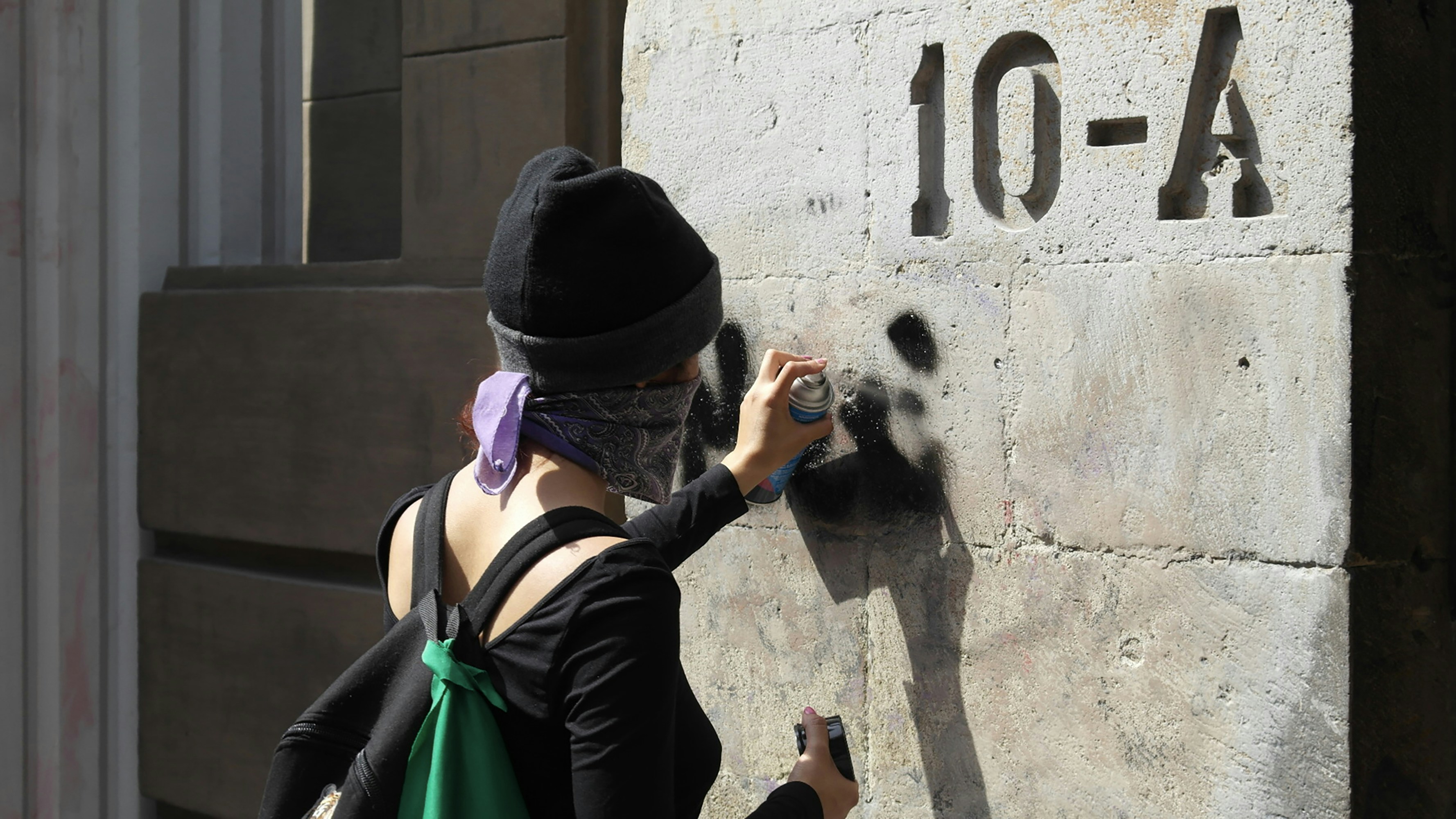 A person is spray-painting on a wall.