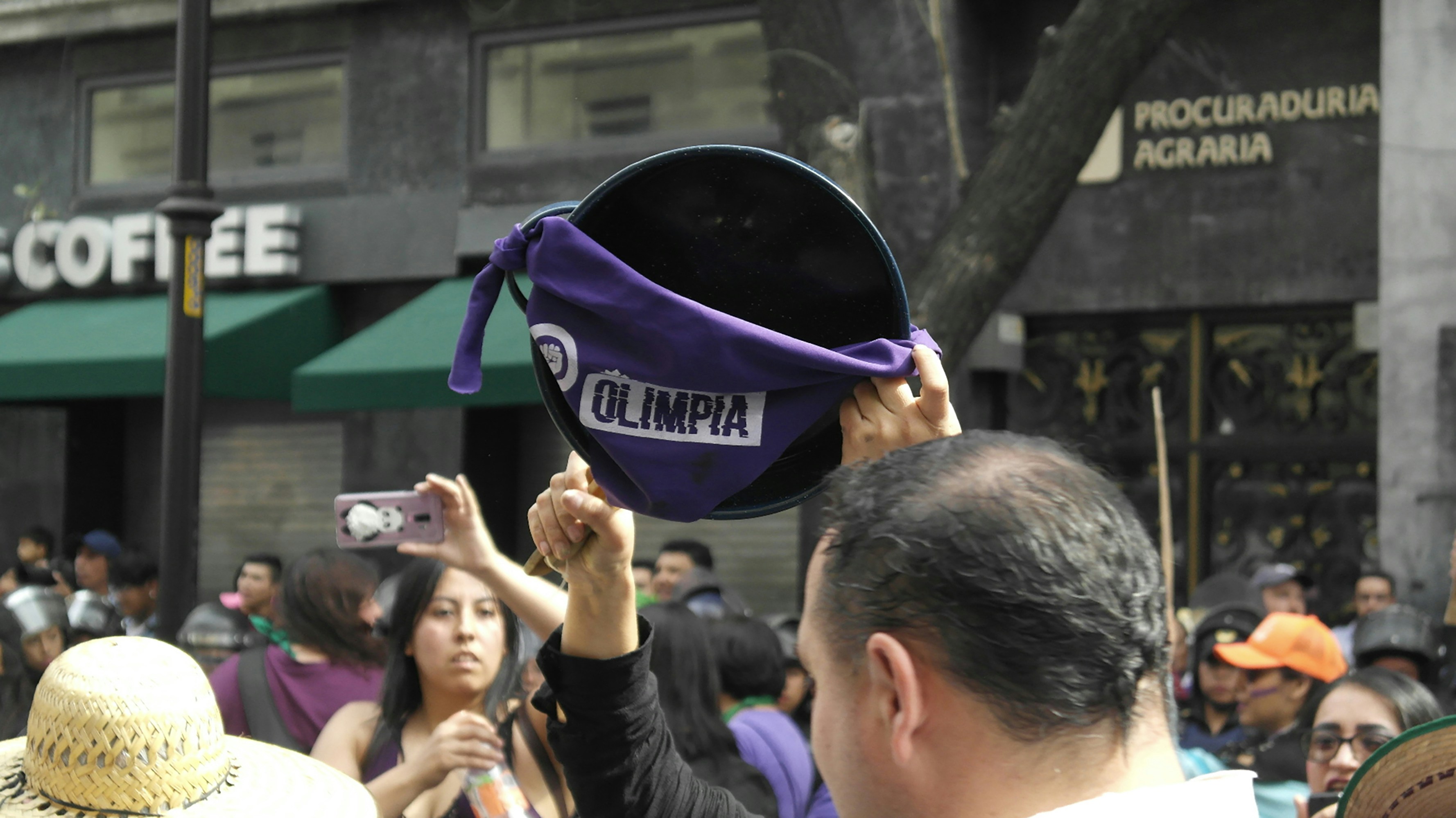 Protester raises a purple hat in the air.