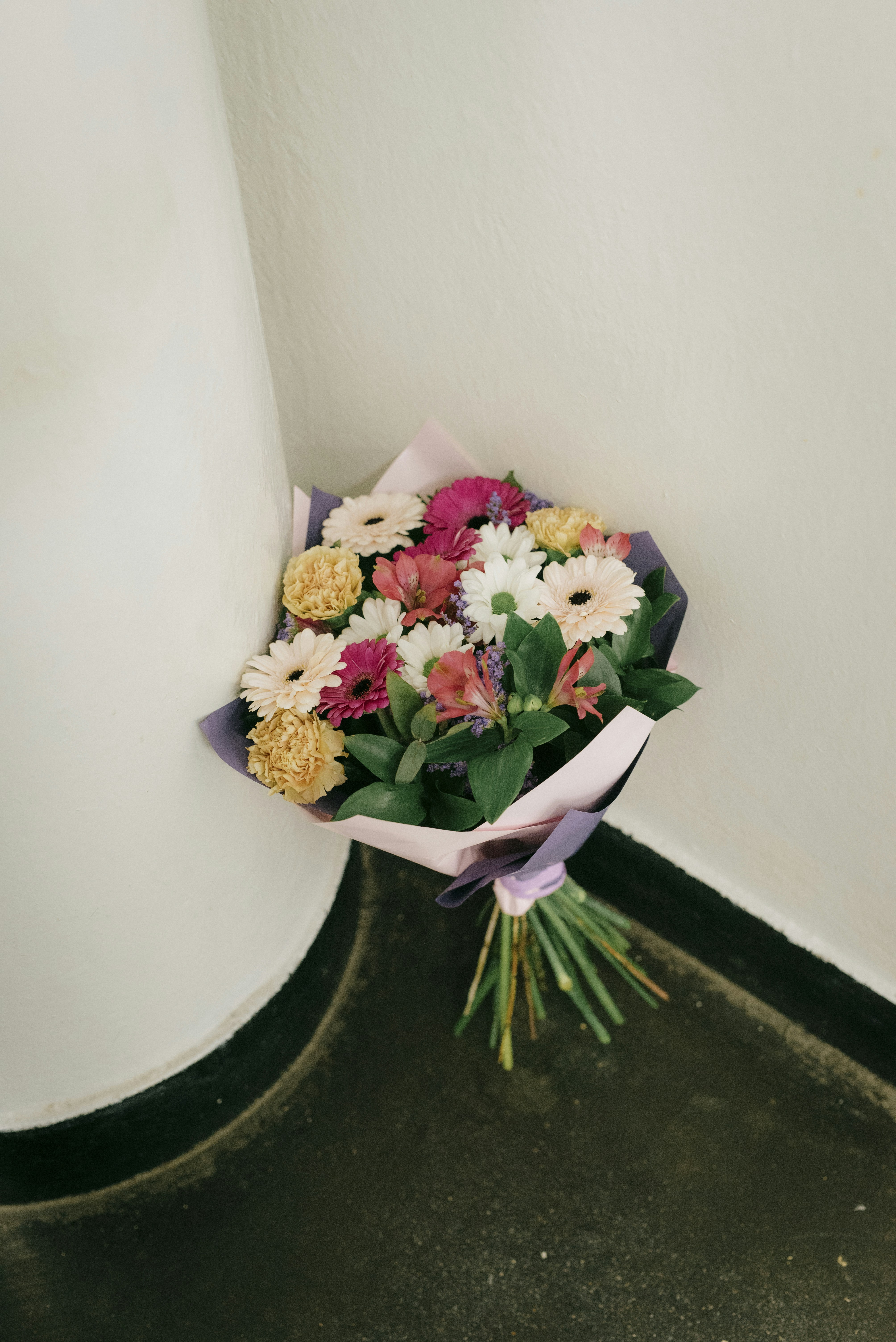 A bouquet of colorful flowers leans against the wall.