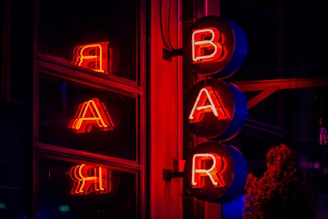 The illuminated neon sign spells out "bar."