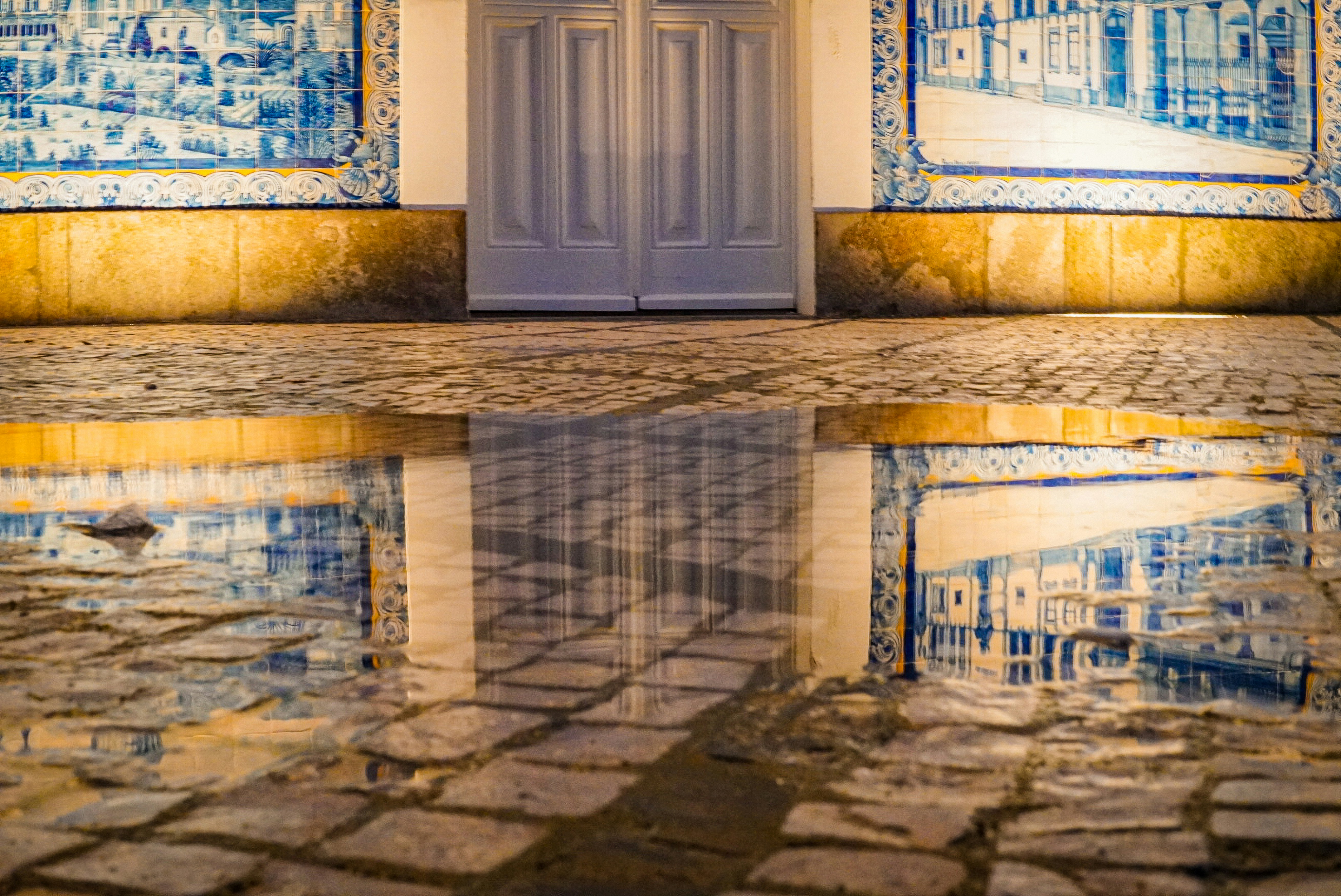 Water reflects a building's facade and door.