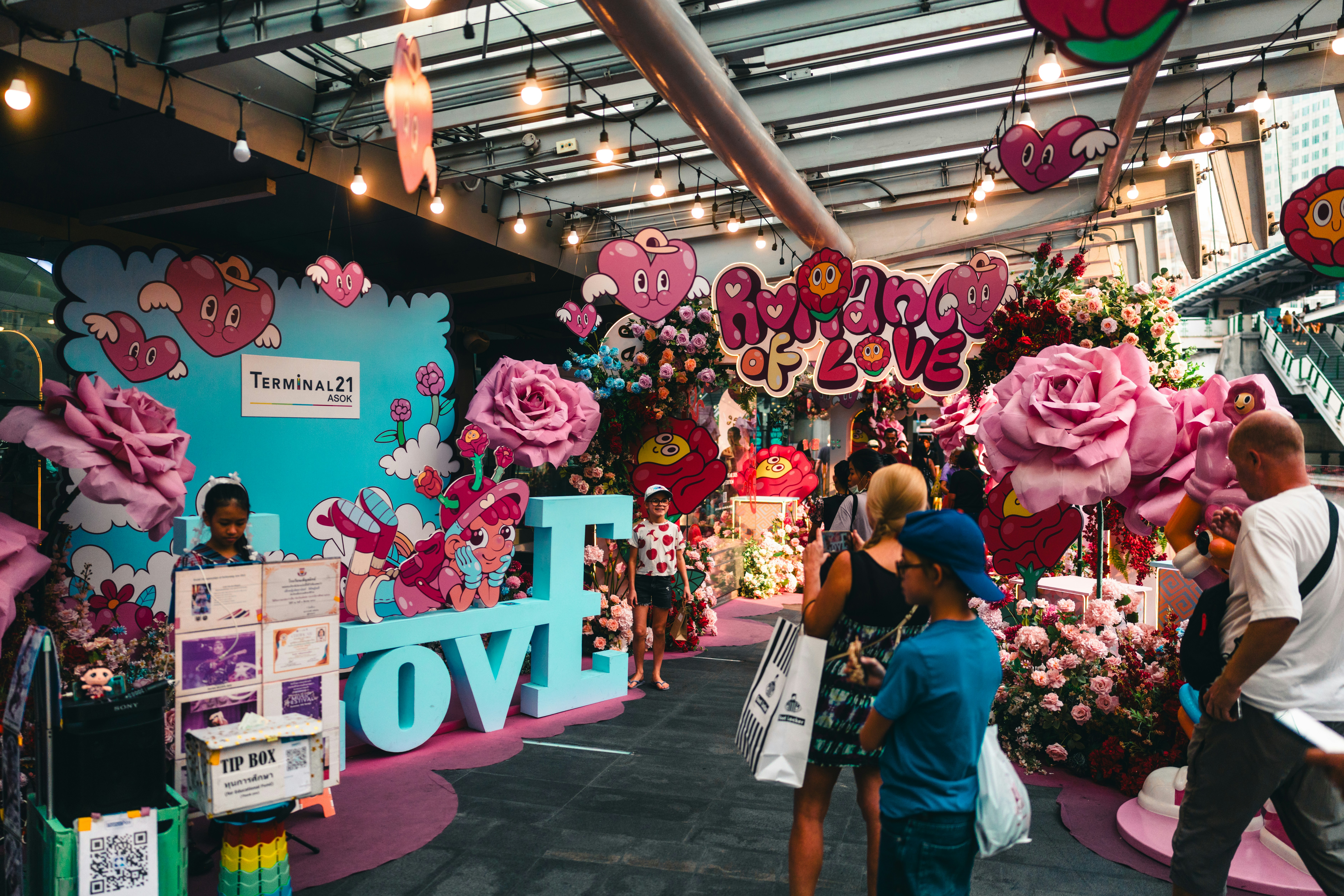 People walk through a colorful, love-themed display.