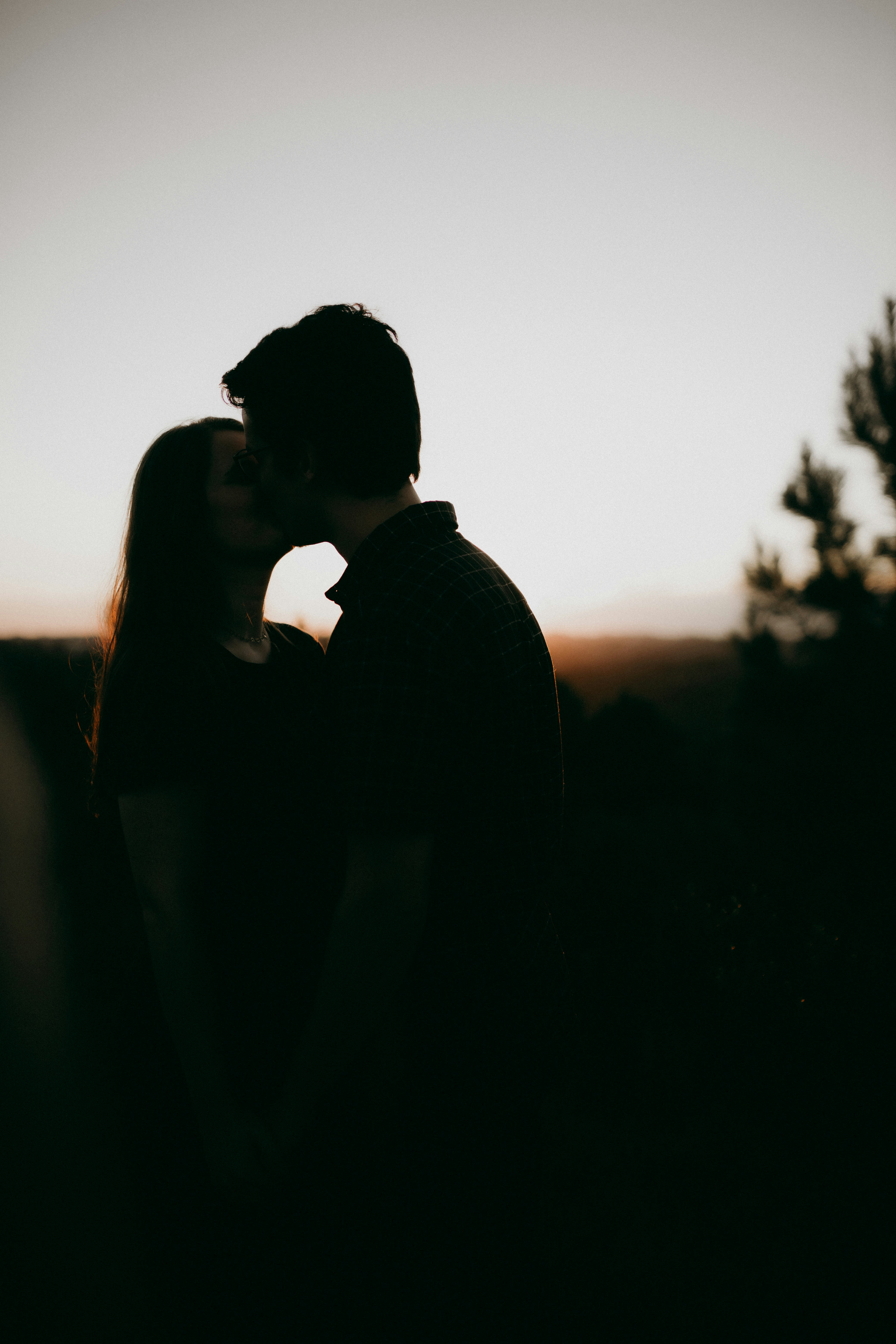 Couple shares a kiss as the sun sets.