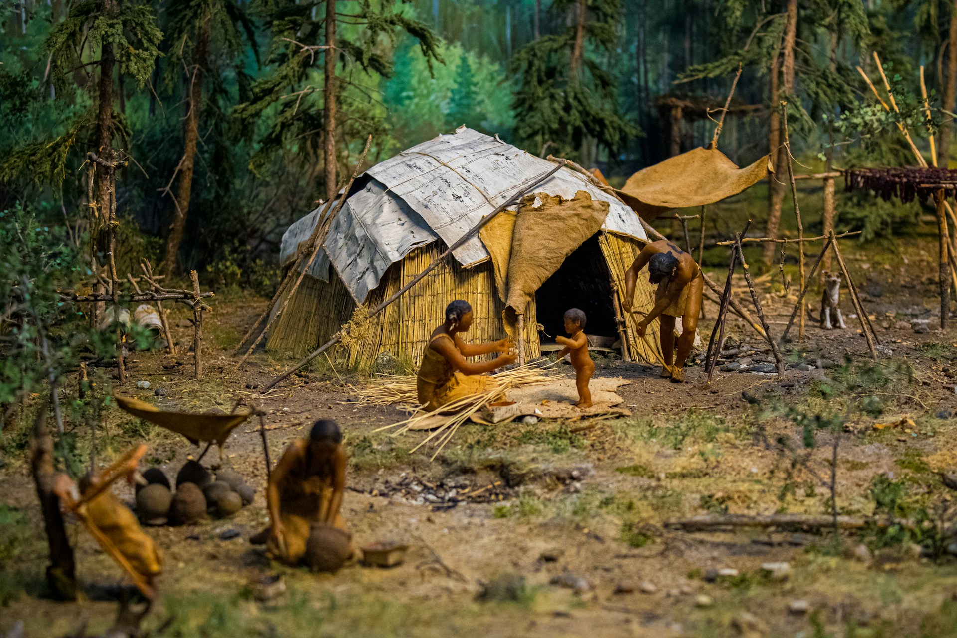 People are shown living in a primitive settlement.