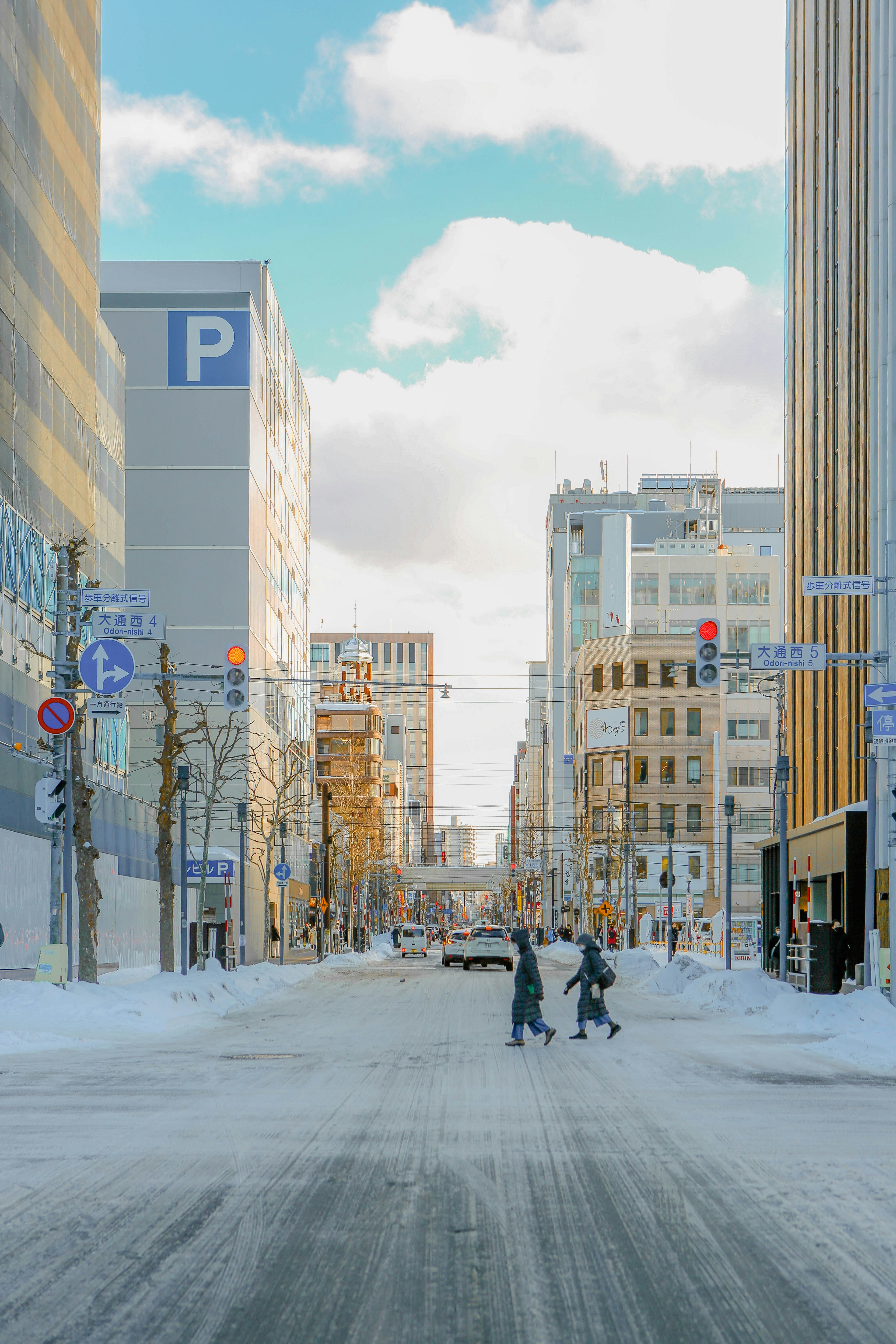 建物や歩行者がいる雪に覆われた街の通り。