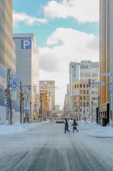 Snowy city street with buildings and pedestrians.
