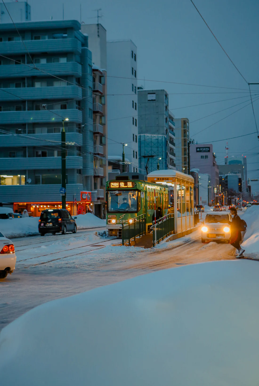 รถรางวิ่งผ่านถนนที่หิมะปกคลุมหนาในเมืองซัปโปโรยามเย็น