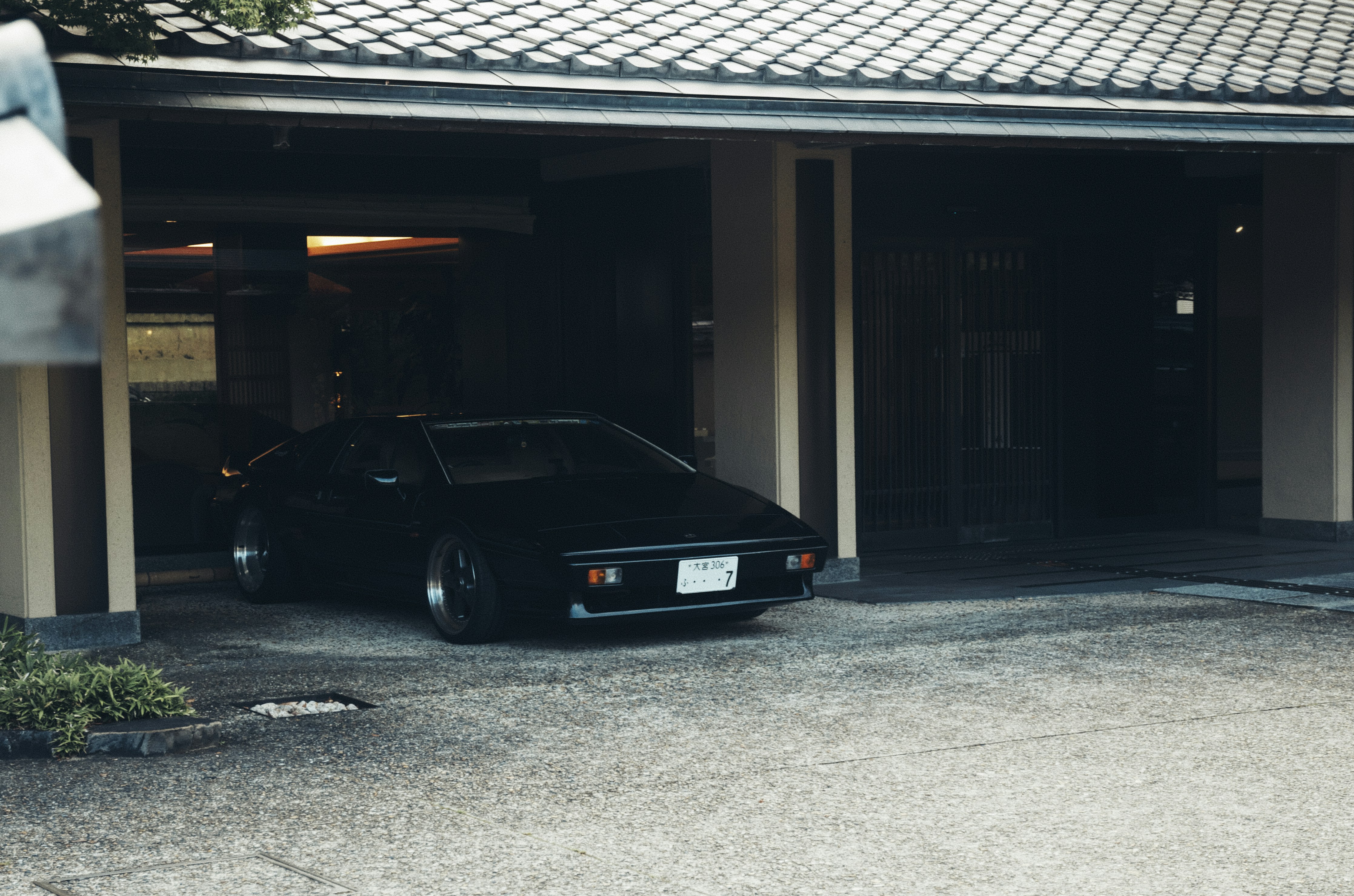 A black car is parked under a carport.