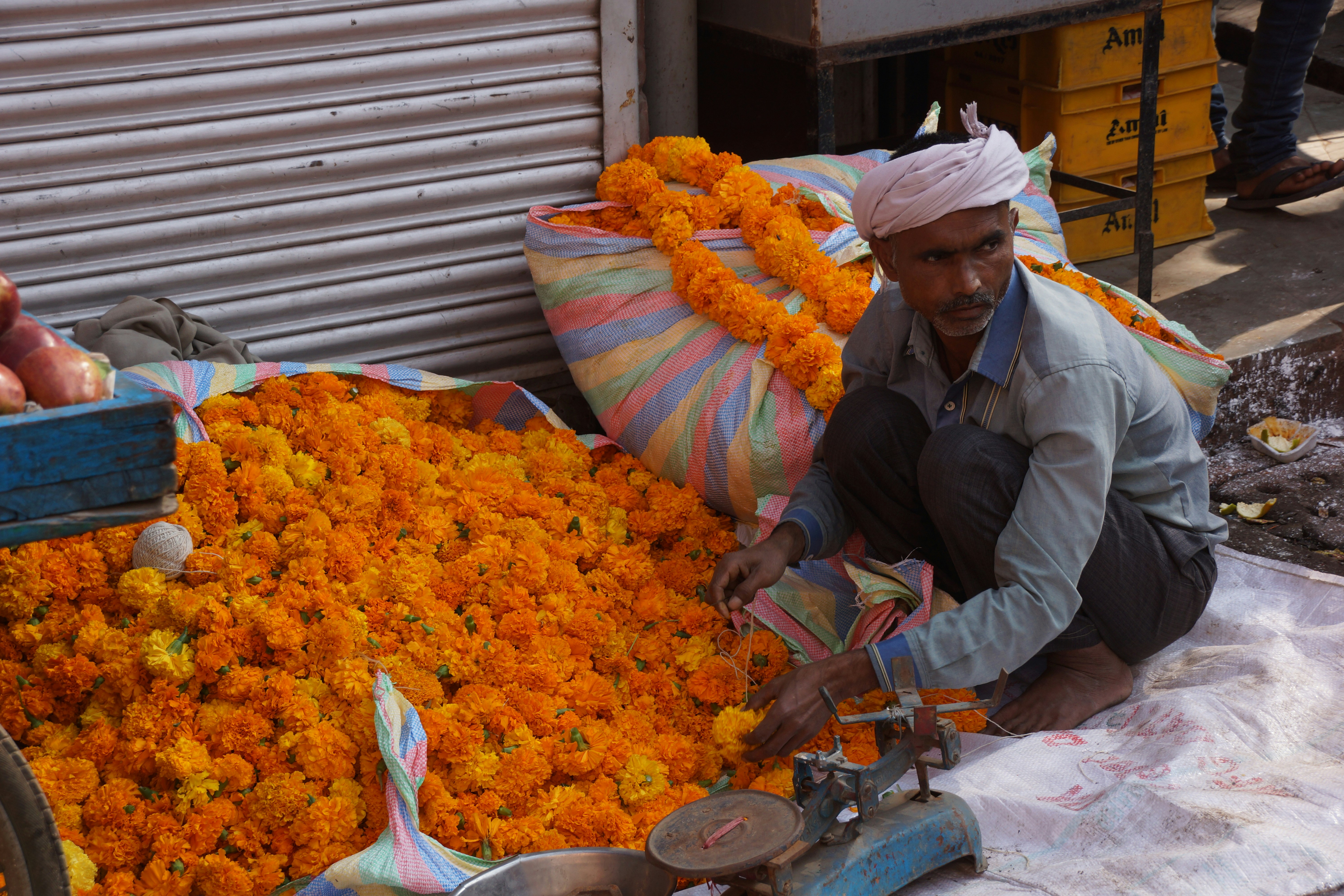 A flower vendor weighs marigold blossoms for sale.