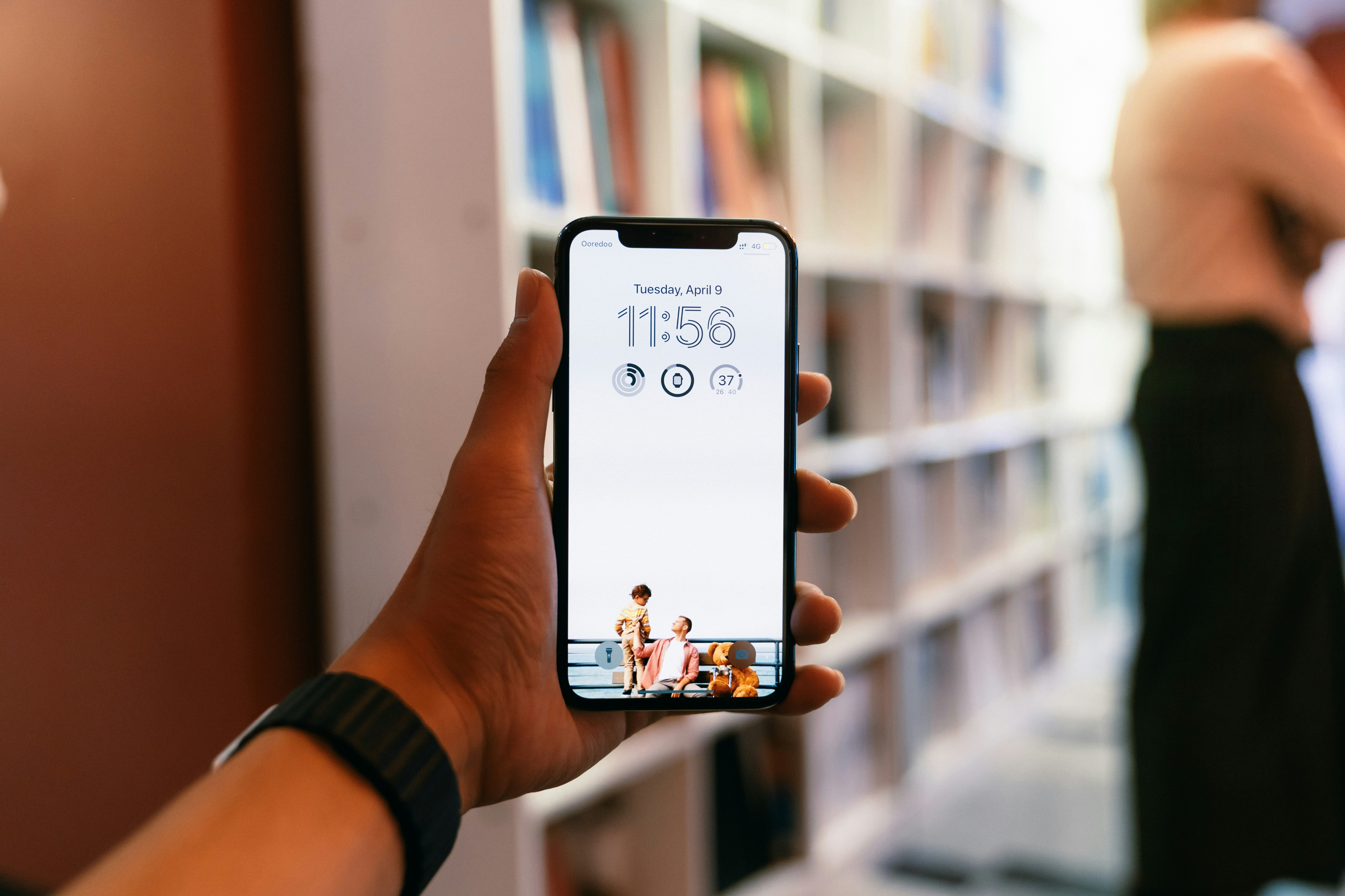 Sebuah tangan memegang smartphone dengan jam.