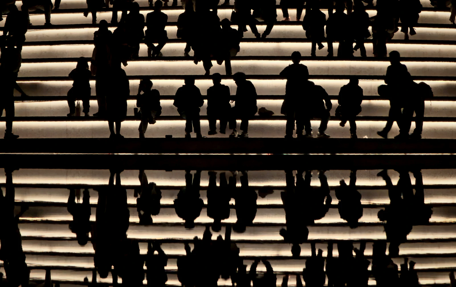 People silhouetted moving up illuminated stairs