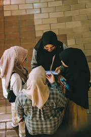 Four women look at a phone together.