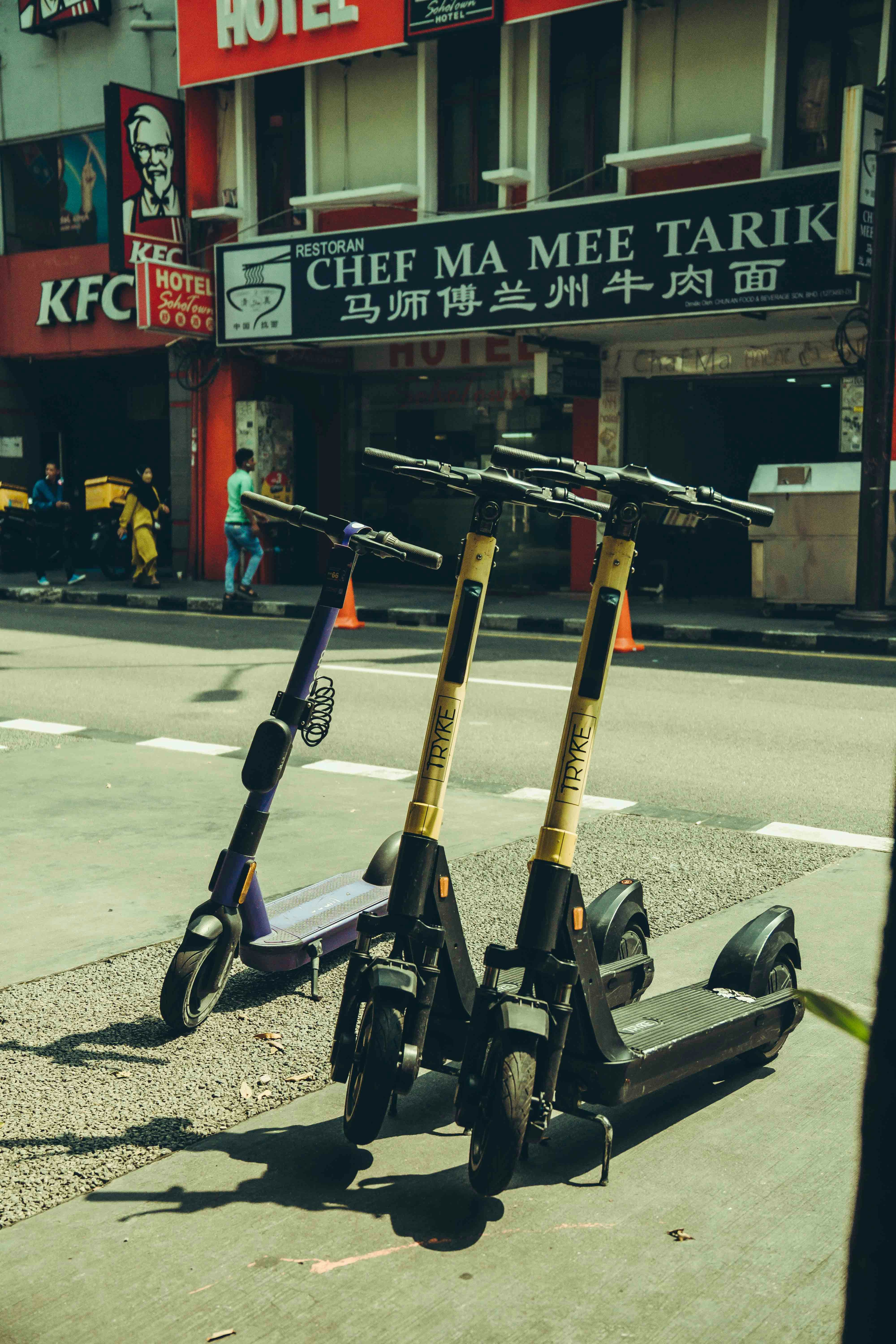 Electric scooters sit on a sunny city street.