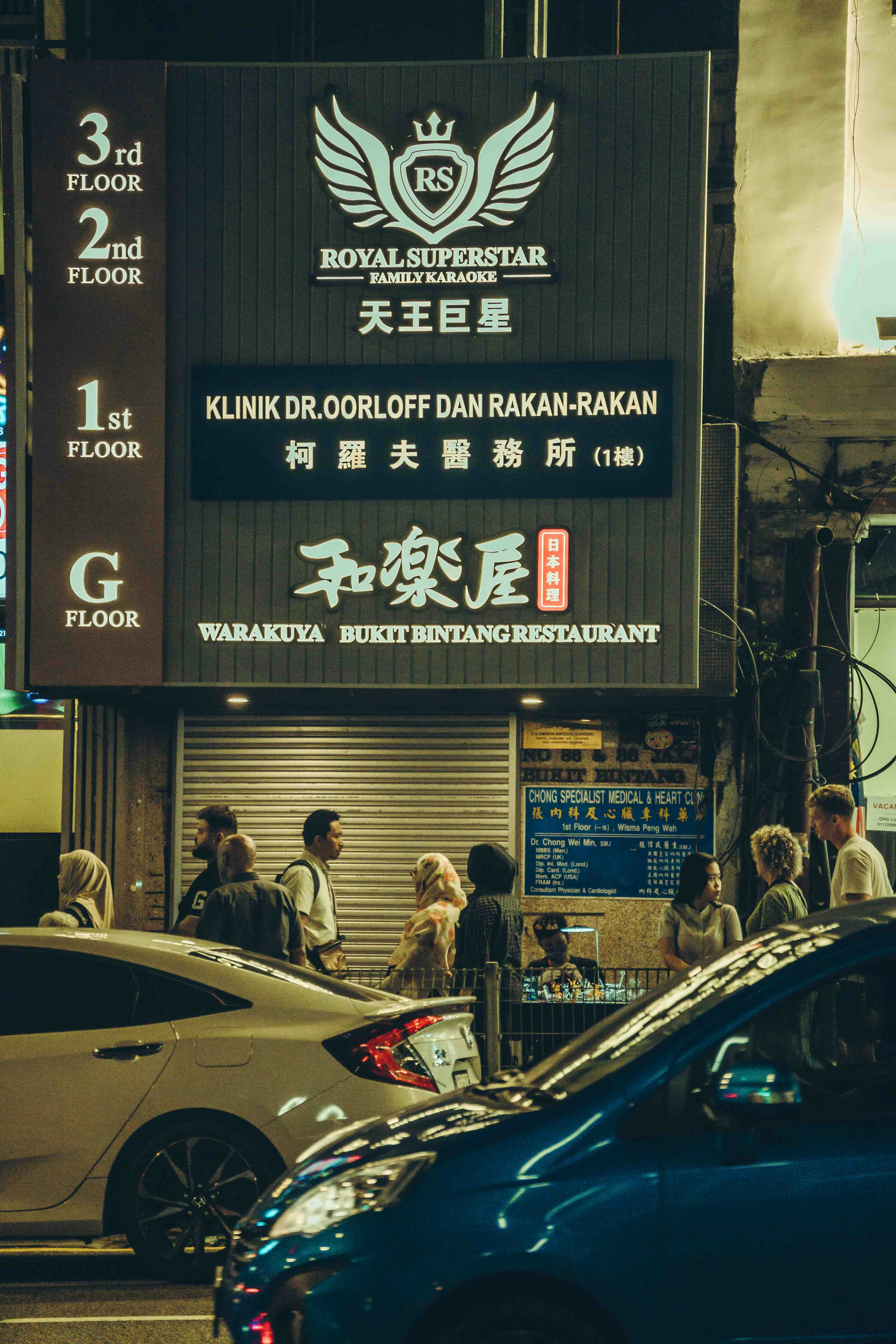 A building sign is seen with people and cars.