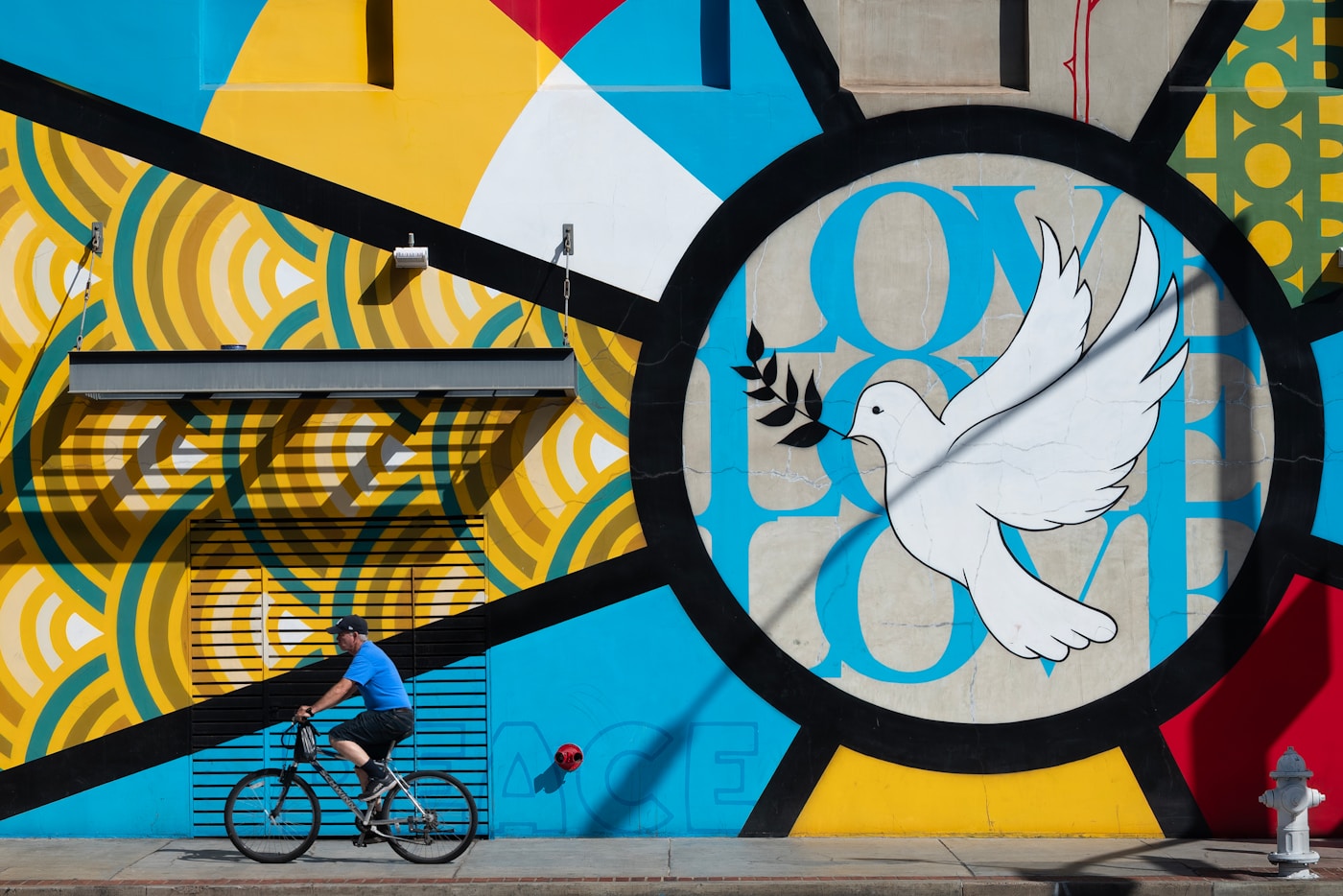 Ciclista passa davanti a un murales colorato con simboli di pace