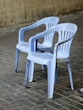 Two blue plastic chairs sit outdoors.