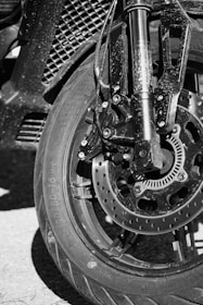 Motorcycle wheel and front suspension in black and white.