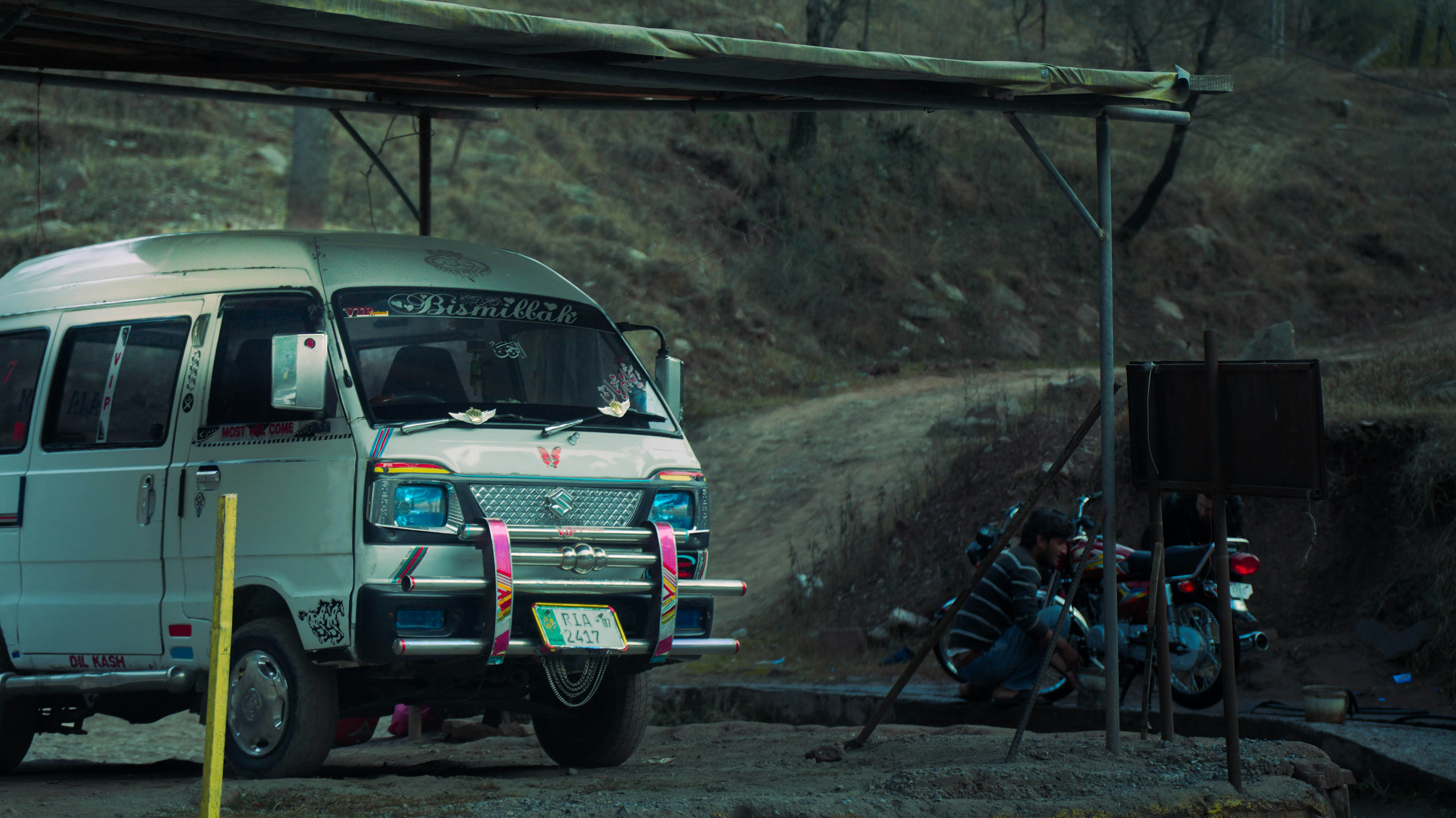 A van and motorcycle are parked near a road.