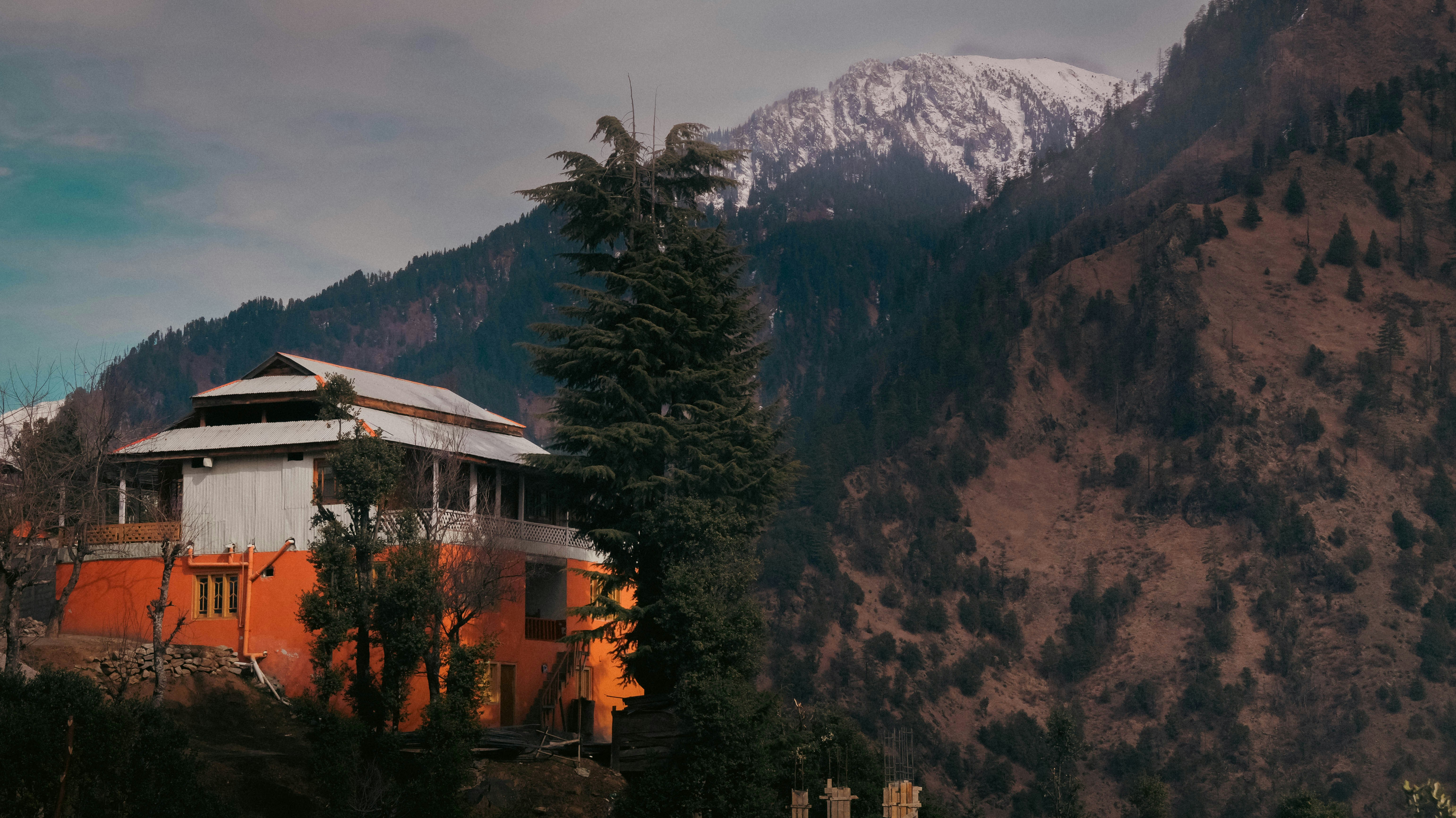 Mountain house with snow-capped peaks in background.