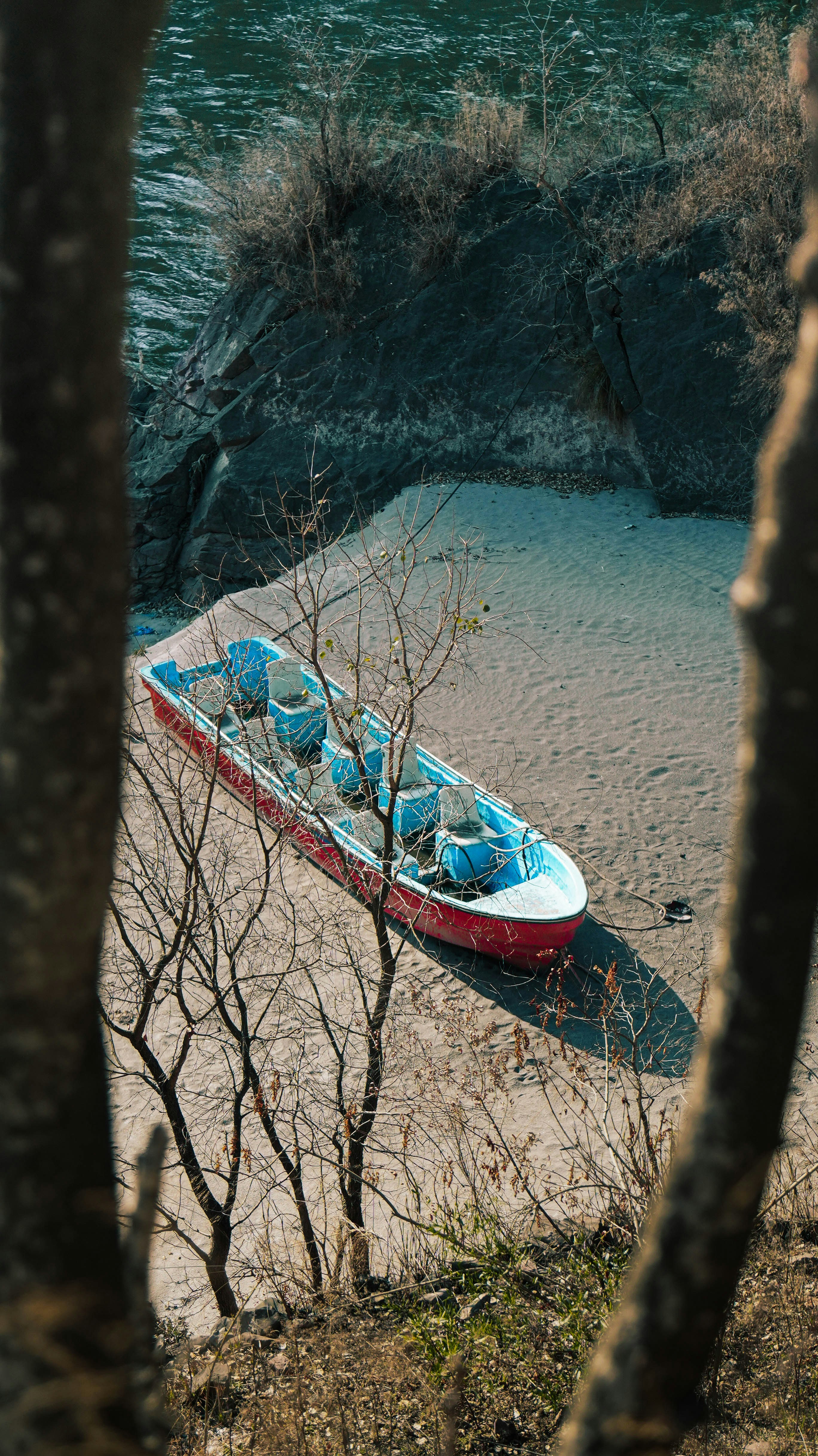 A red boat rests on a sandy beach.