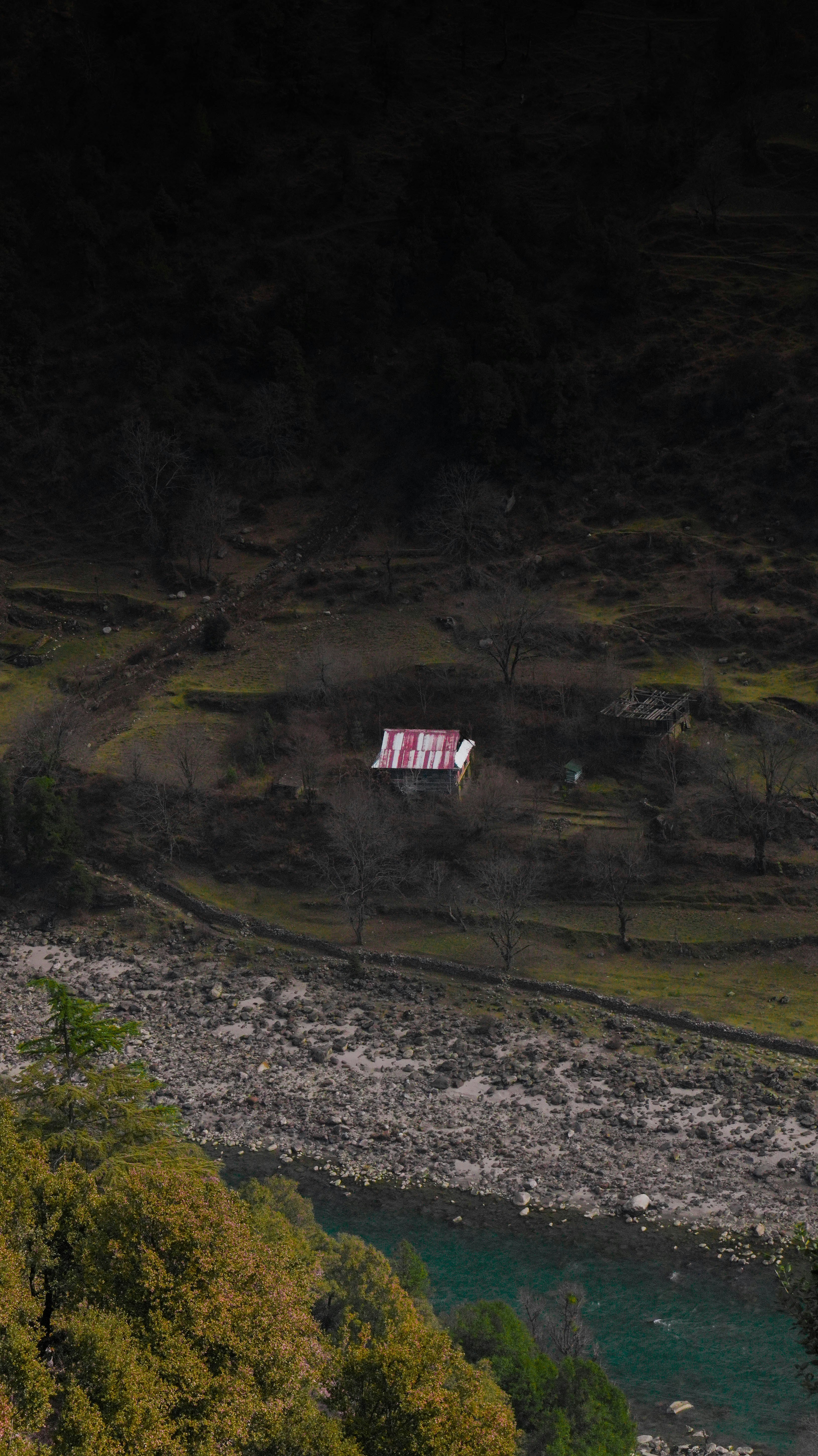 A lone house sits by a river in the mountains.
