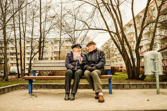 Elderly couple happily sitting on a bench together.