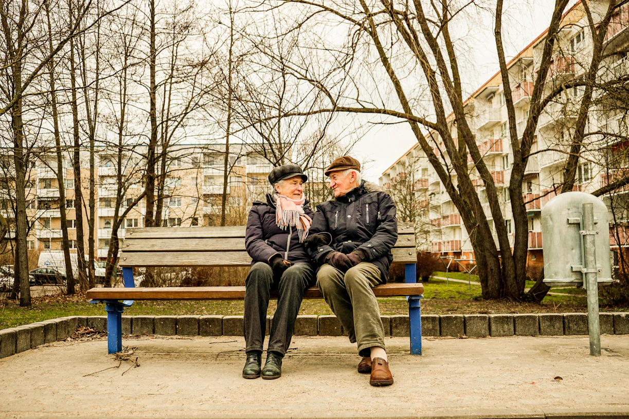 Elderly couple happily sitting on a bench together.