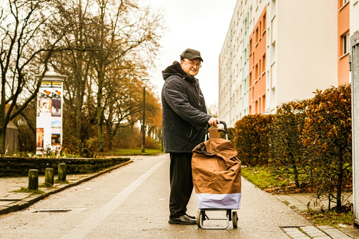 Man with a shopping cart on a street, illustrating contactless volunteering in community service projects.