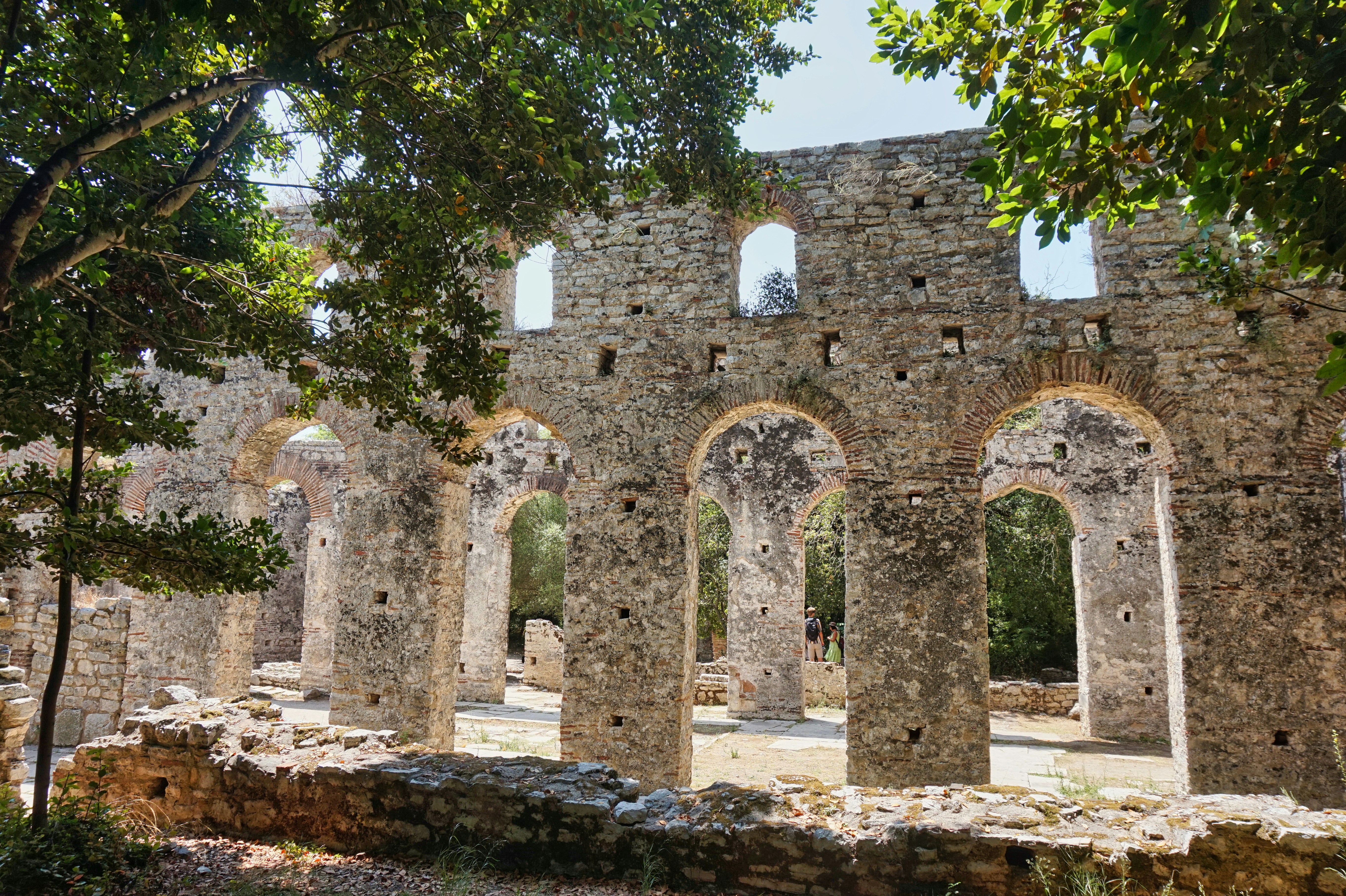 Ancient stone ruins under the shade of trees.