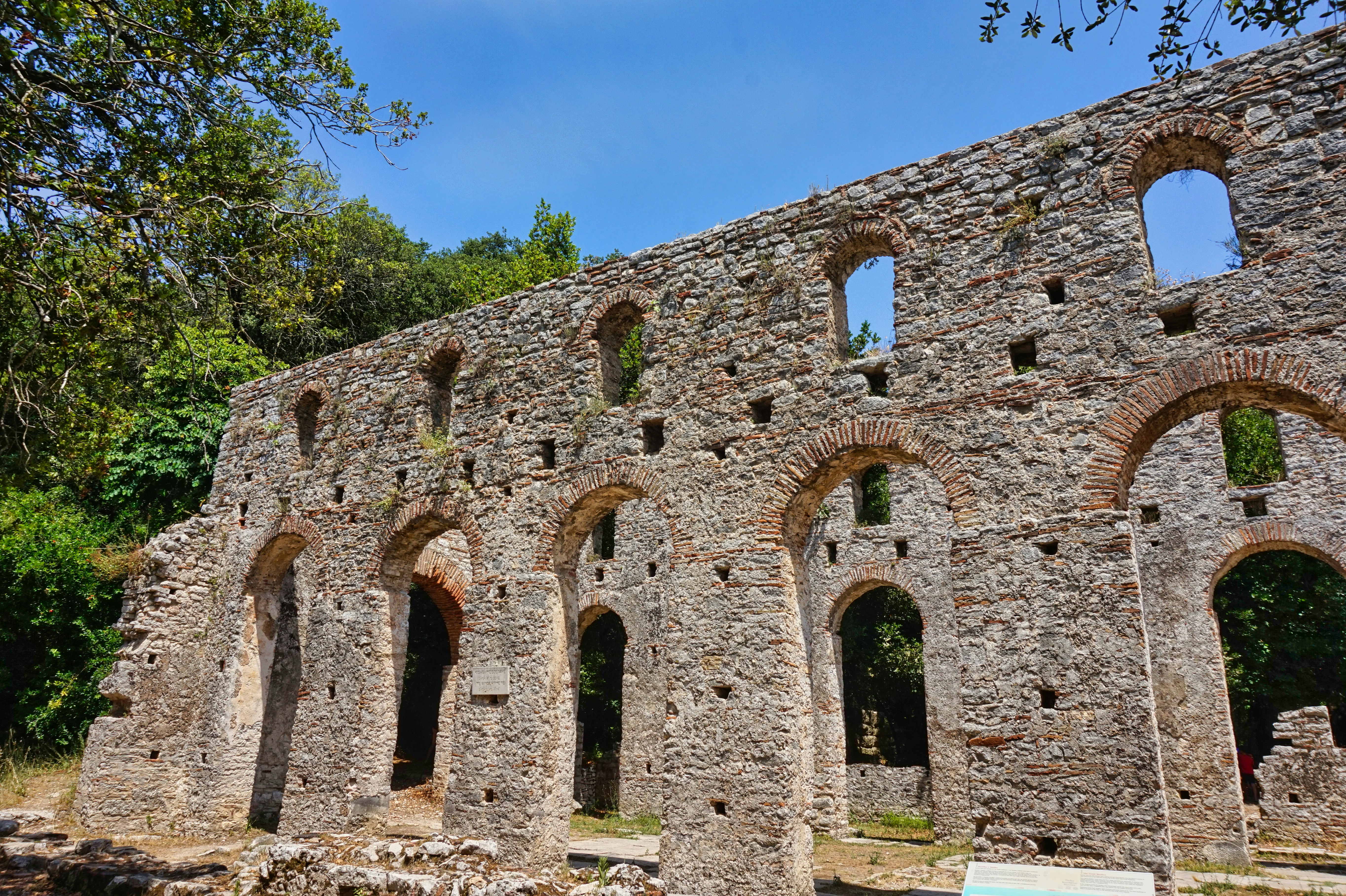 View of ancient amphitheater ruins in Butrint National Park amid greenery