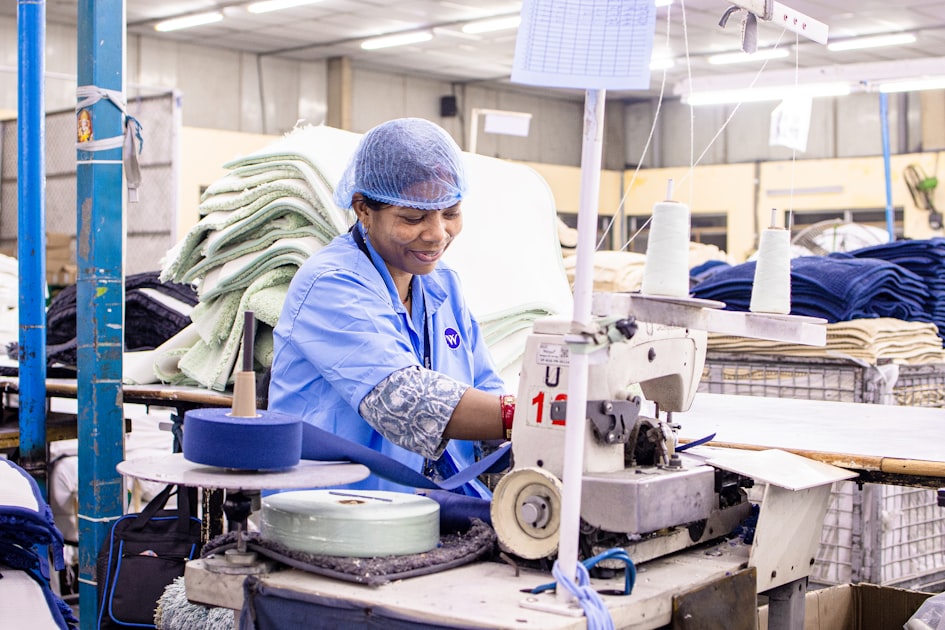 A seamstress works at an industrial sewing machine, illustrating the cut-and-sew stage of plush toy production
