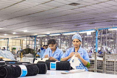 Factory workers are stitching fabric in a production line.