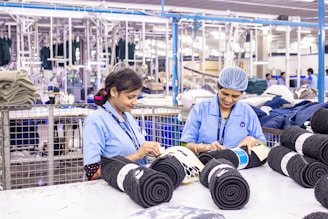 Workers sort fabric rolls in a factory.