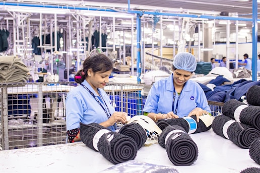 Workers sort fabric rolls in a factory.